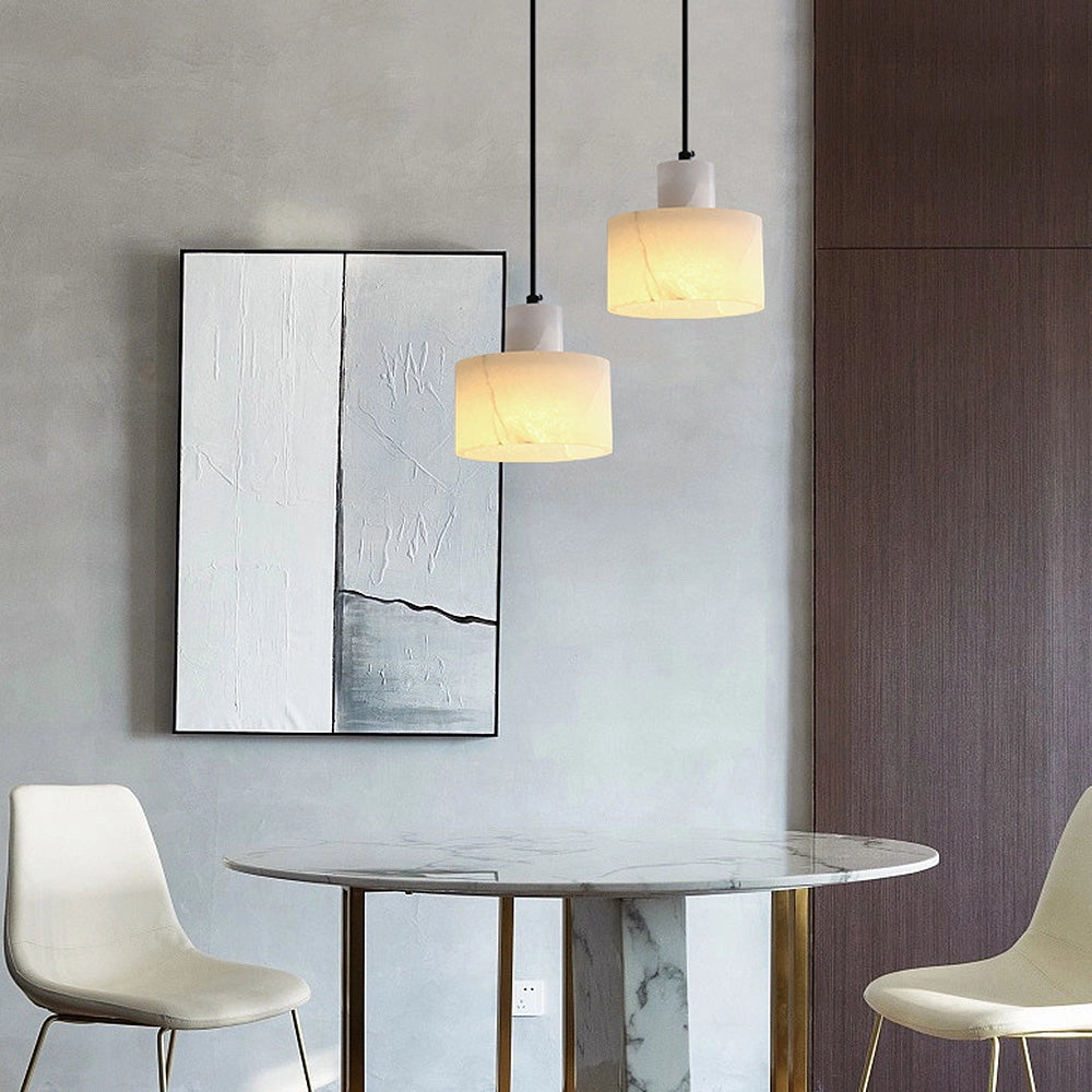 A minimalist ceiling lamp made from natural stone, featuring a sleek rectangular alabaster pendant, illuminating a modern interior space with white and wooden furniture.
