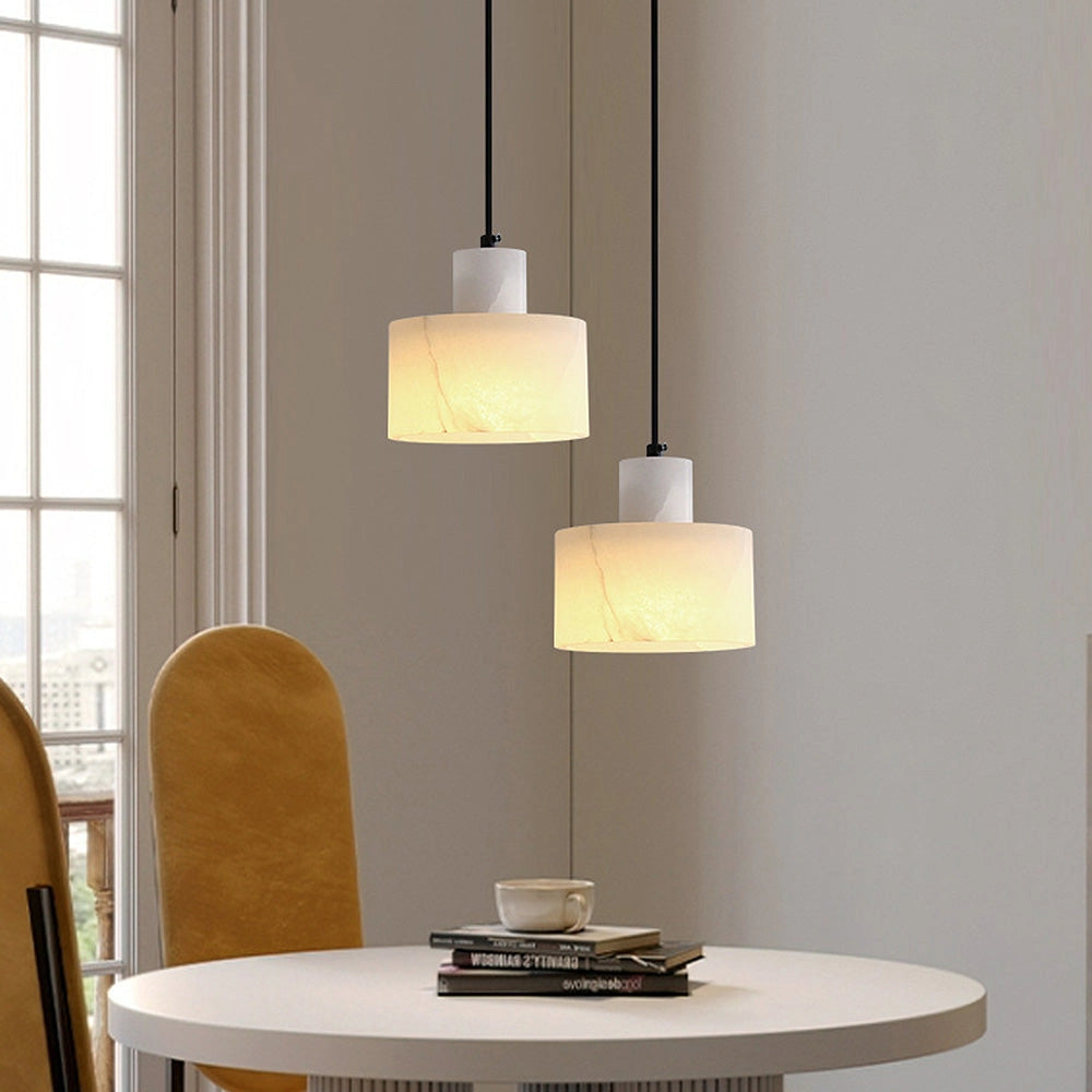 Luxury Alabaster Pendant Light made from natural stone hanging from a minimalist ceiling, illuminating a modern interior with wooden furniture and large windows.