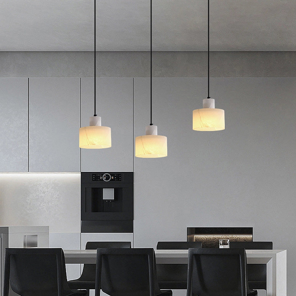 Luxury Alabaster Pendant Light hanging from the ceiling in a modern living room with minimalist interior design, featuring wooden flooring and a light-colored table.