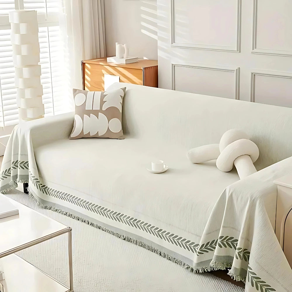Luxurious beige couch cover with a houndstooth pattern draped over a large sofa, styled in an elegant living room setting. The cover fits a 180x340cm sofa and complements interior design elements with its sophisticated textile, creating a comfortable and stylish atmosphere.