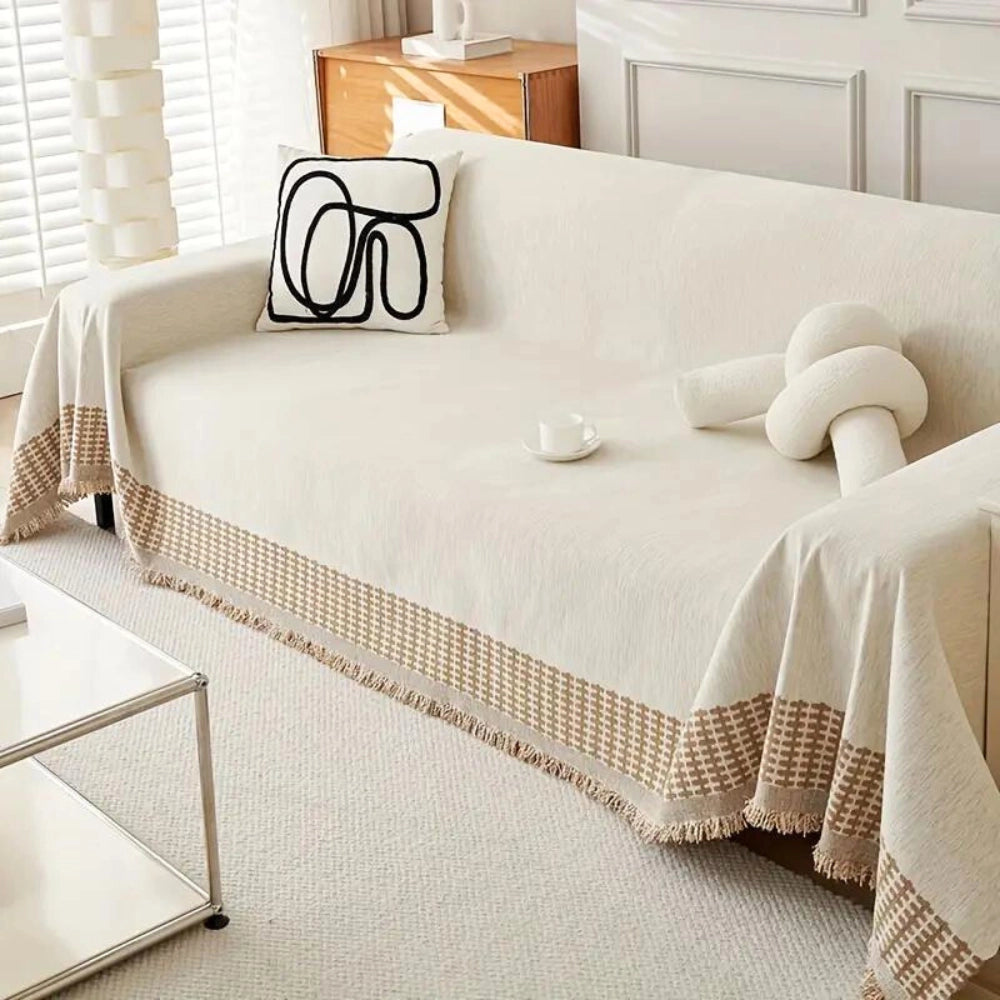Luxury beige couch cover with houndstooth pattern draped over a sofa, set in an elegantly decorated room with wooden flooring and a nearby table.