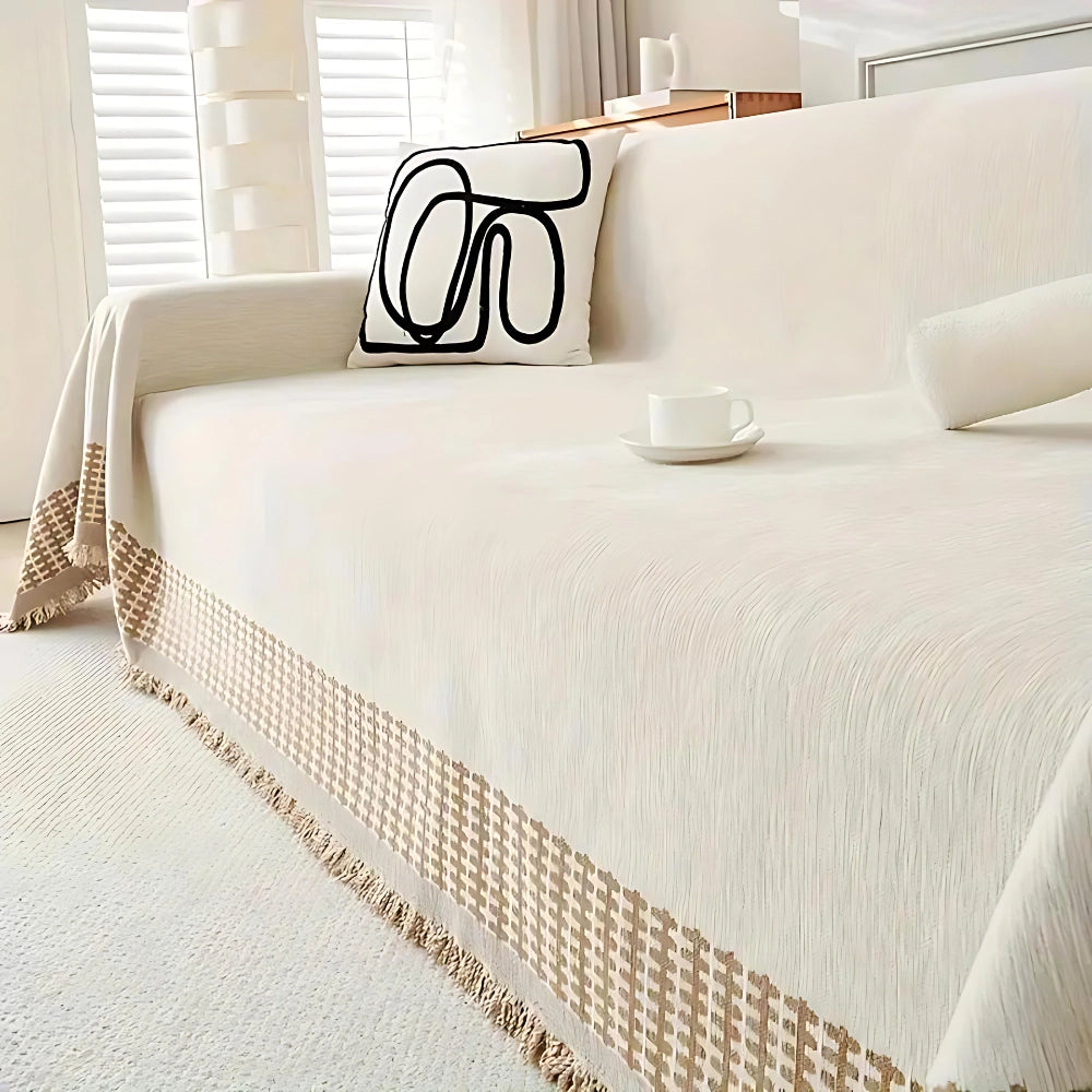 Luxury beige couch cover with a houndstooth pattern in a latte color, elegantly draped over a rectangular sofa, set against a stylish interior design backdrop with wooden flooring.