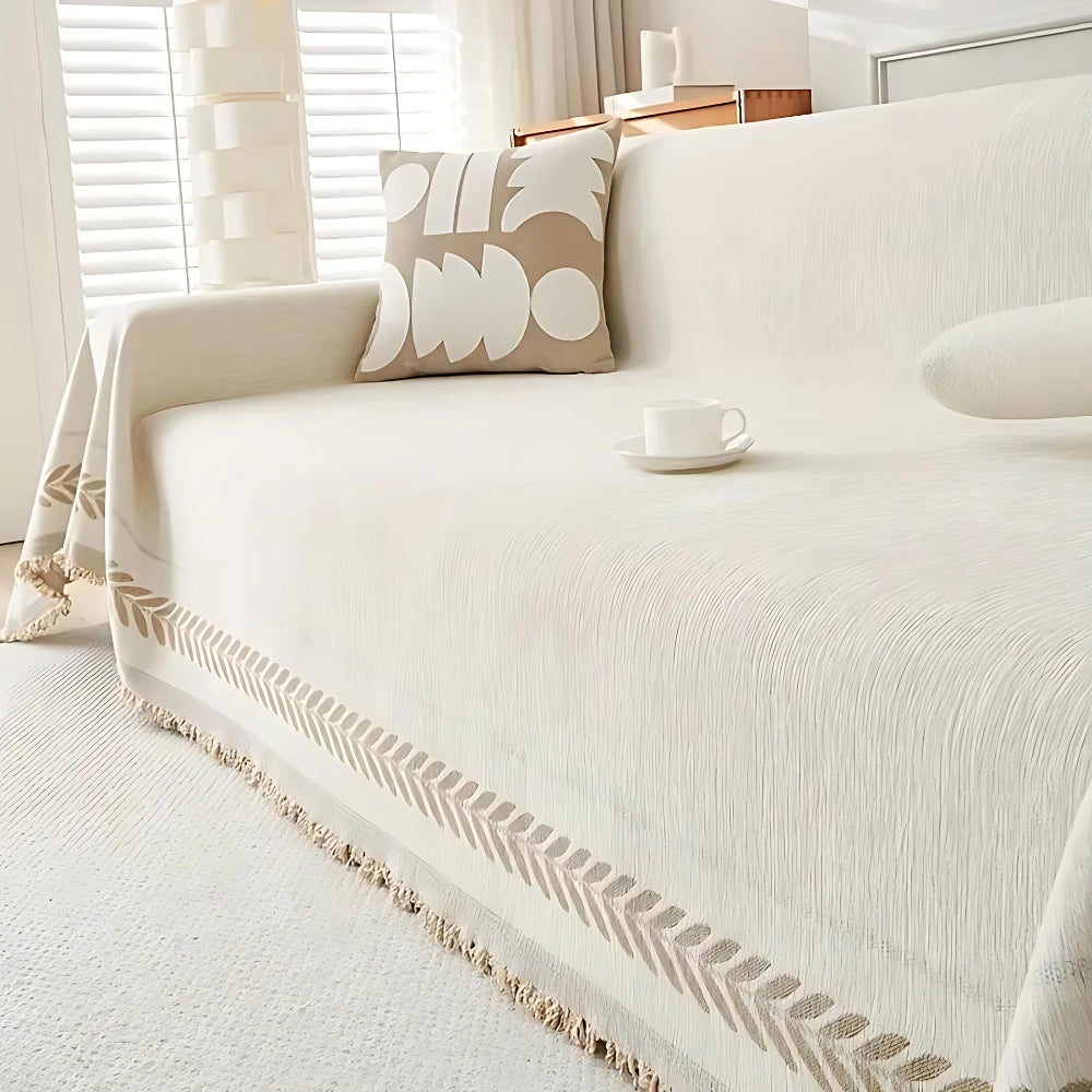 Luxury beige couch cover with houndstooth pattern draped over a rectangular sofa, set against a wooden floor in a stylishly designed interior. The elegant cover adds a sophisticated touch to the decor with its wheat spike color variant, measuring 180x340cm.