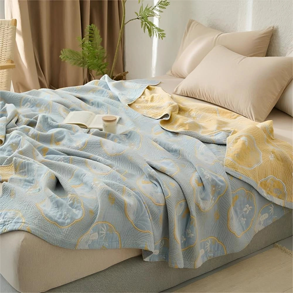 Luxury blue bedding set featuring an ornate gold floral pattern displayed in a well-decorated bedroom. The set includes plush pillows and is placed on a bed frame, surrounded by elegant furniture, enhancing the room's interior design.