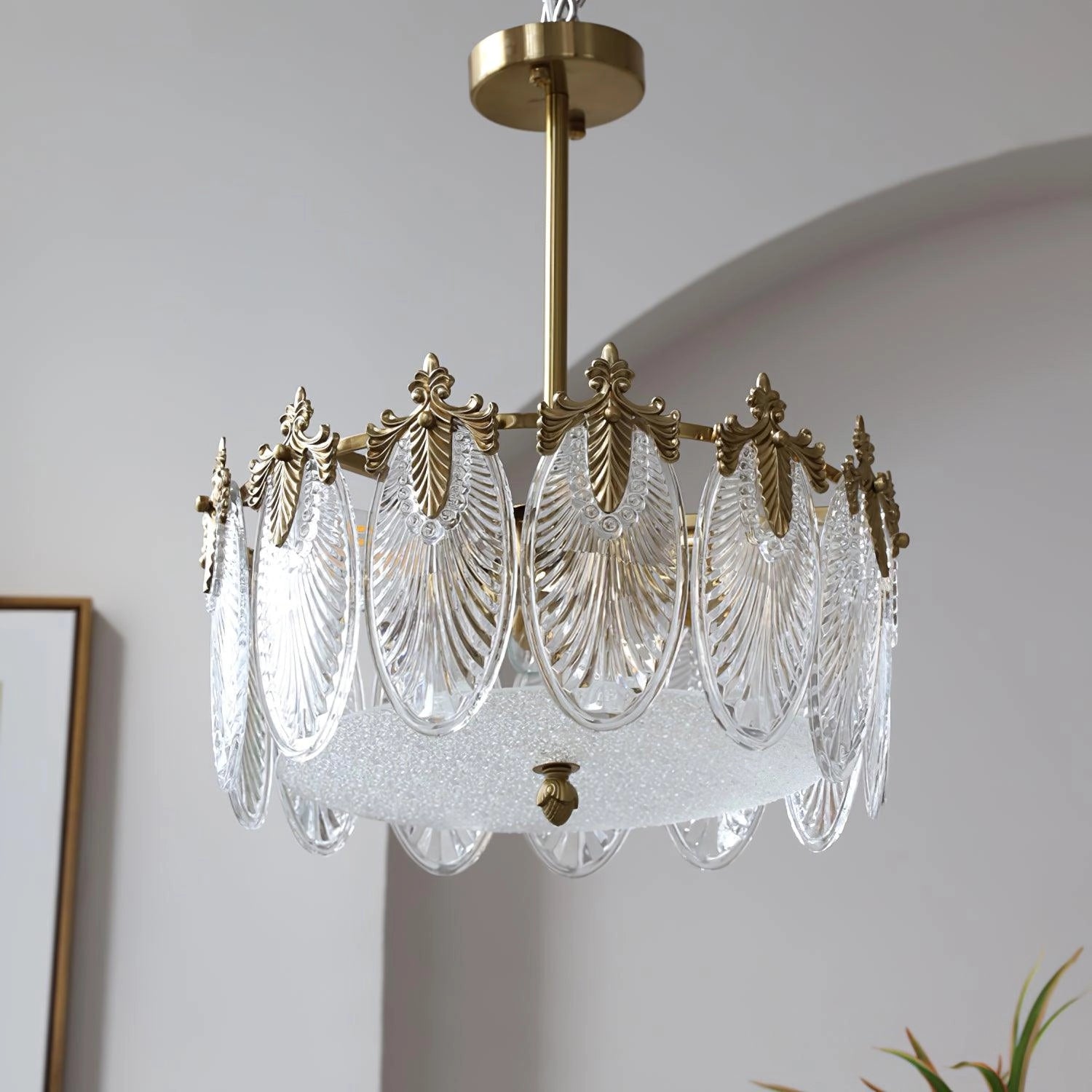 Luxury crystal chandelier with gold leaf vintage design, hanging from the ceiling and illuminating a white interior space.