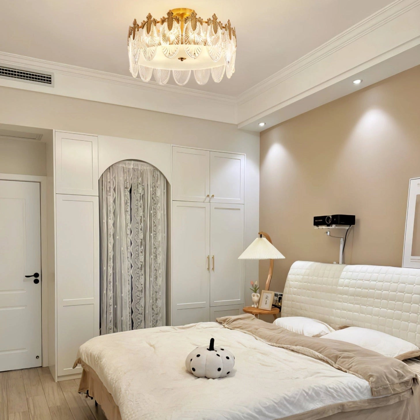 Elegant luxury crystal chandelier with gold leaf finish, hanging in a vintage-styled room featuring white walls, wooden furniture, and sophisticated interior design.
