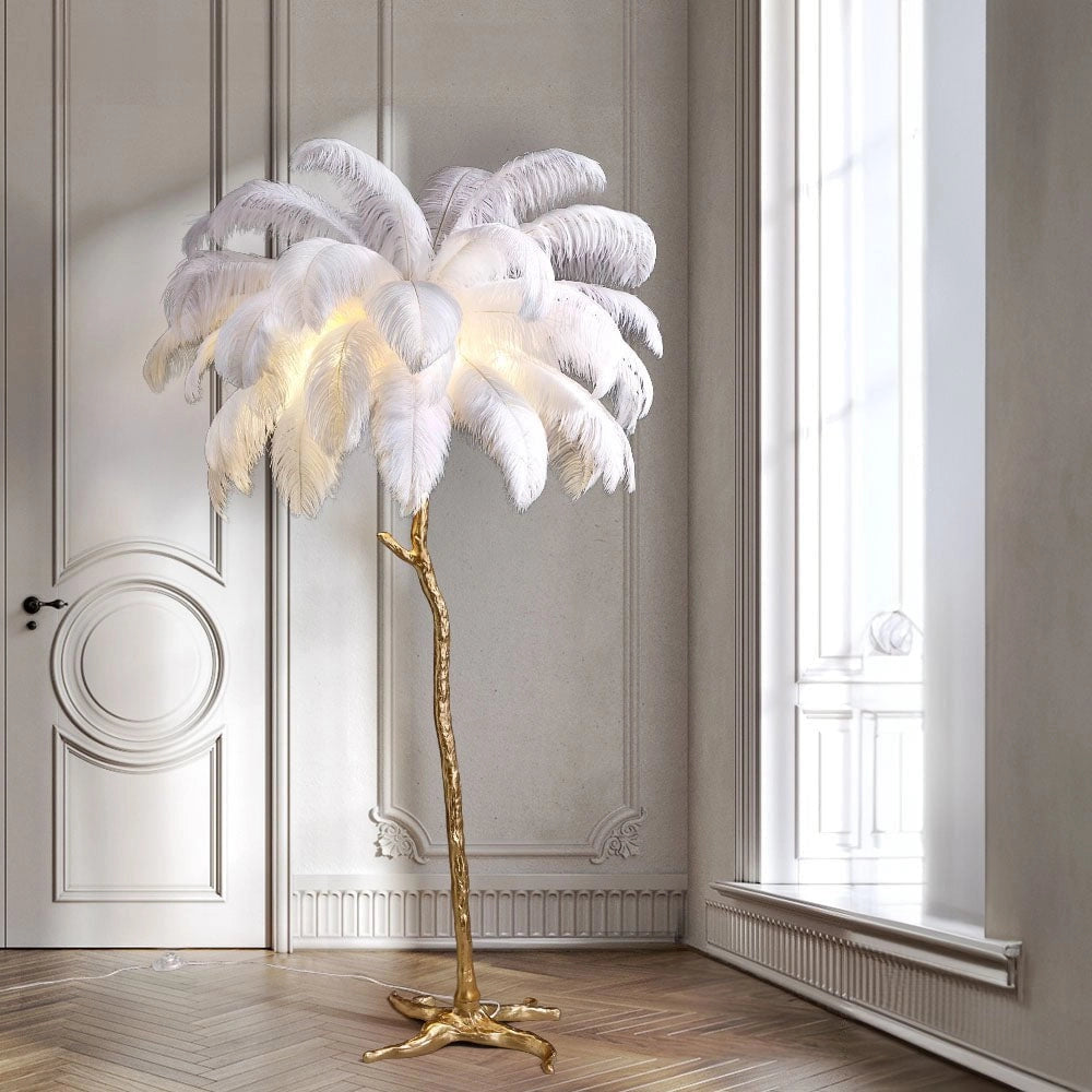 Luxury Feather Floor Lamp with Gold Palm Tree Art Deco design, featuring white feathers, placed in an elegantly designed room with wooden flooring, plants, and a large window.