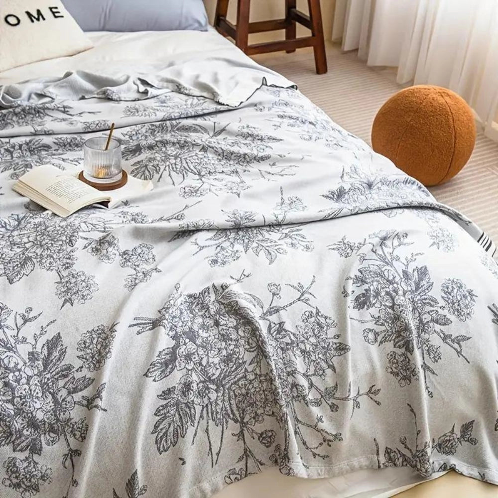 Luxury floral cotton duvet cover in a botanical design, displayed on a neatly made bed with a grey and white color scheme, complemented by a sturdy wooden bed frame, exuding comfort and elegance in a stylish bedroom setting.