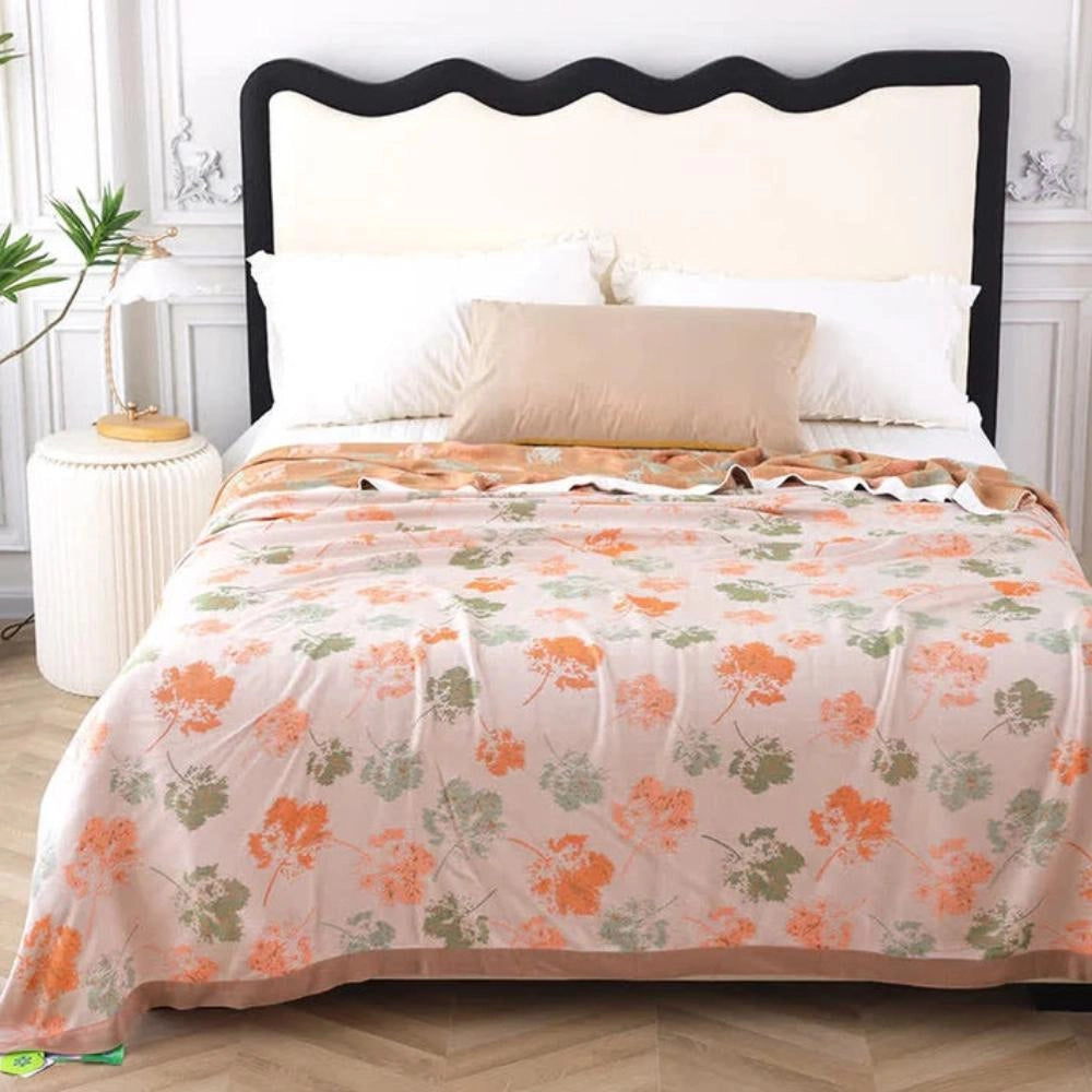 Luxury floral silk comforter in orange draped over a wooden bed in a stylish interior with white and azure accents, featuring a potted plant for added decor.