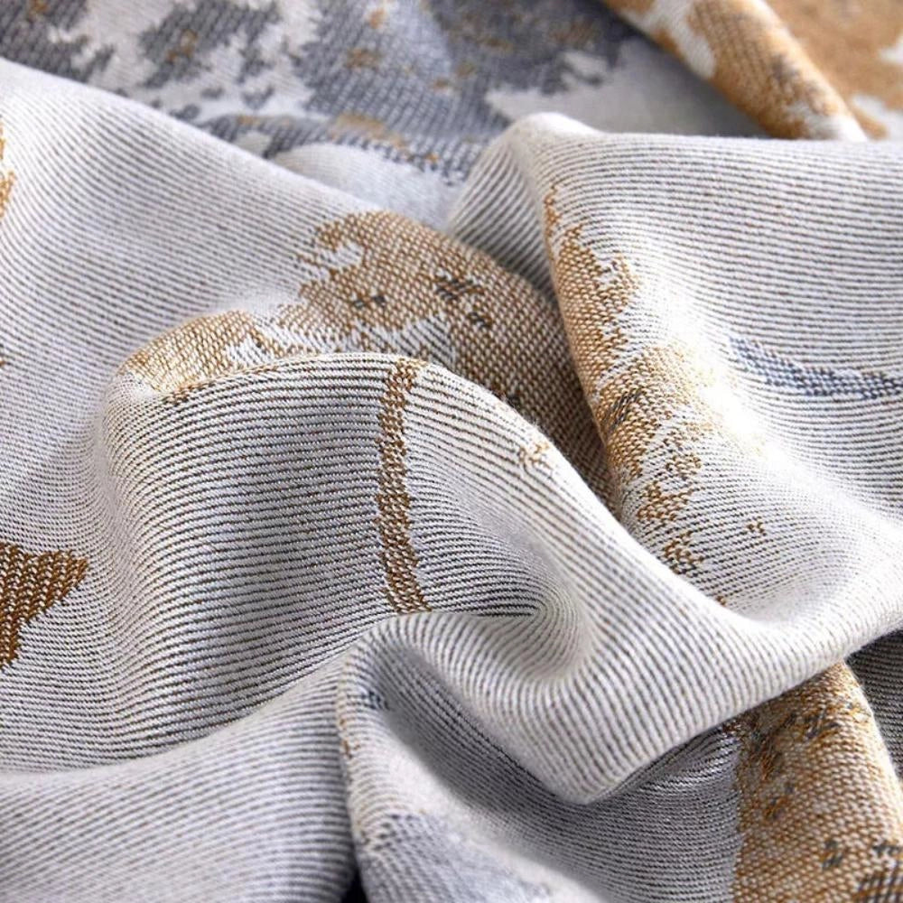 Luxury floral silk comforter in grey with an intricate pattern, displayed on a wooden surface for a close-up view, highlighting its premium silk texture and elegant design.