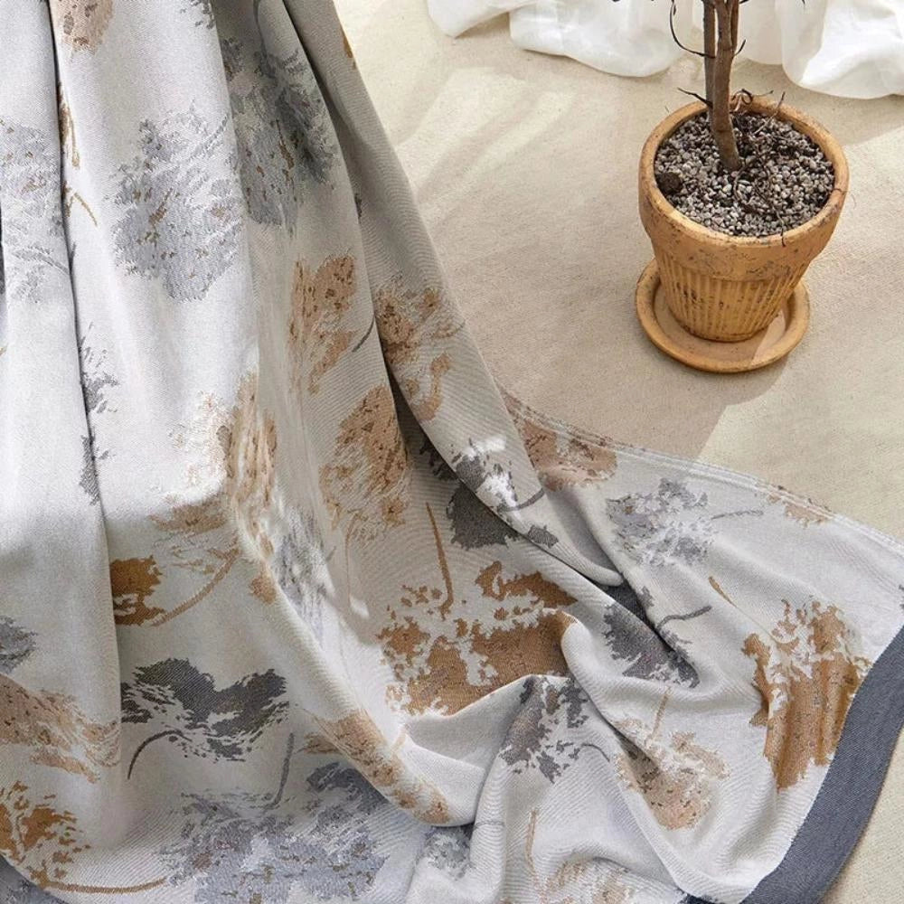 Luxurious white floral silk comforter draped over a table, showcasing its elegant textile design in a stylish interior setting.