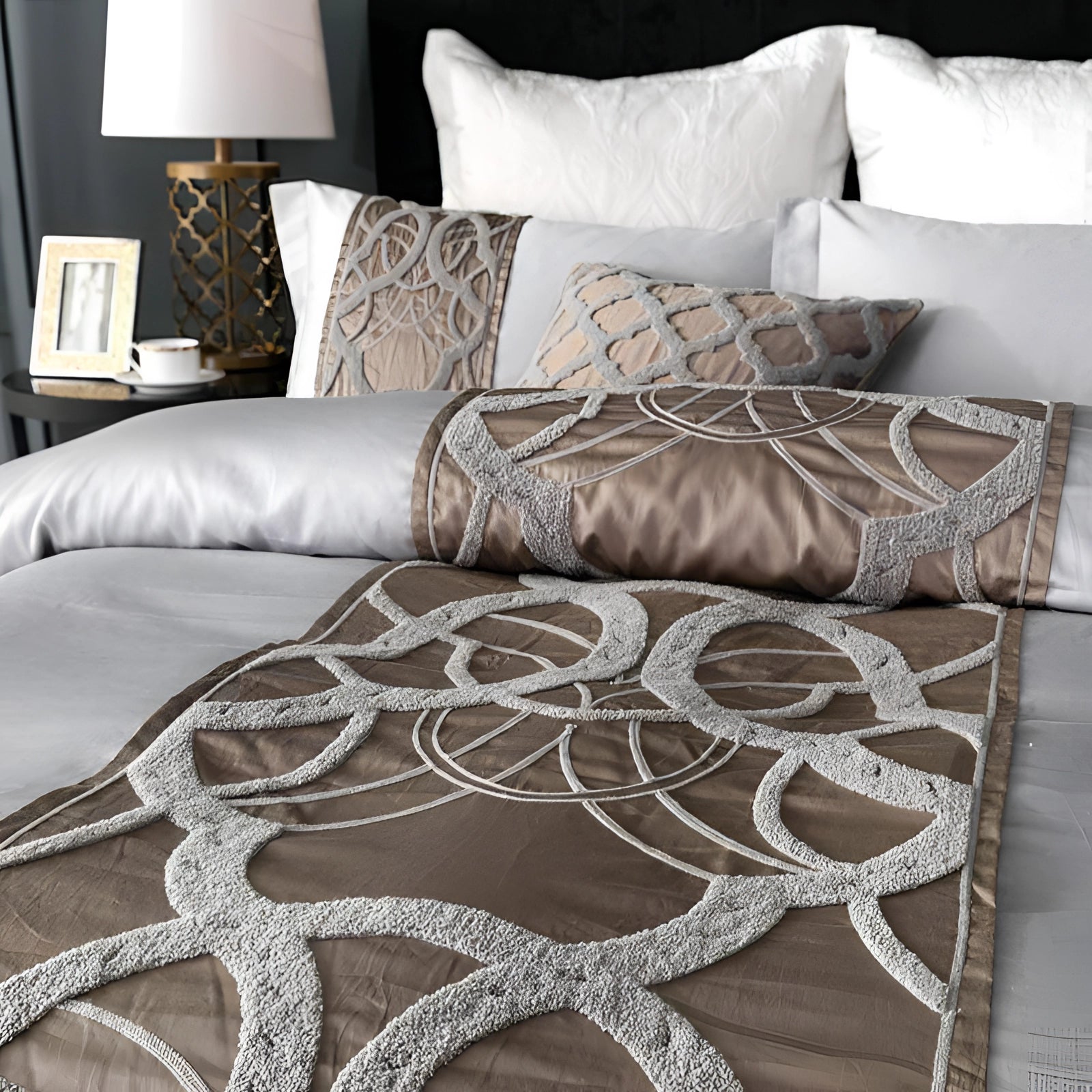 Luxury geometric satin bedding set in taupe gray displayed on a neatly made bed with a soft comforter. The bedding set is surrounded by modern interior design elements, including a couch and decorative pillows, creating a comfortable and elegant atmosphere.