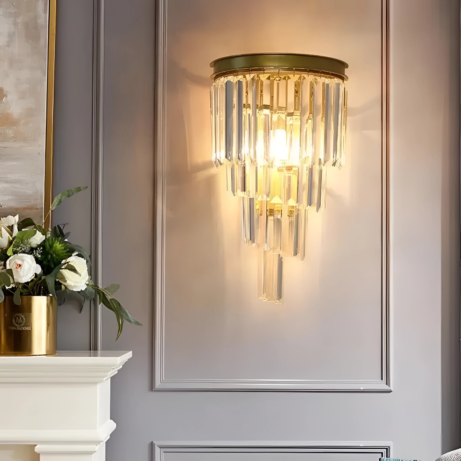 Luxury glass wall sconce with gold accents mounted on a contemporary living room wall, surrounded by stylish interior elements including a houseplant in a decorative flowerpot and other modern decor pieces.