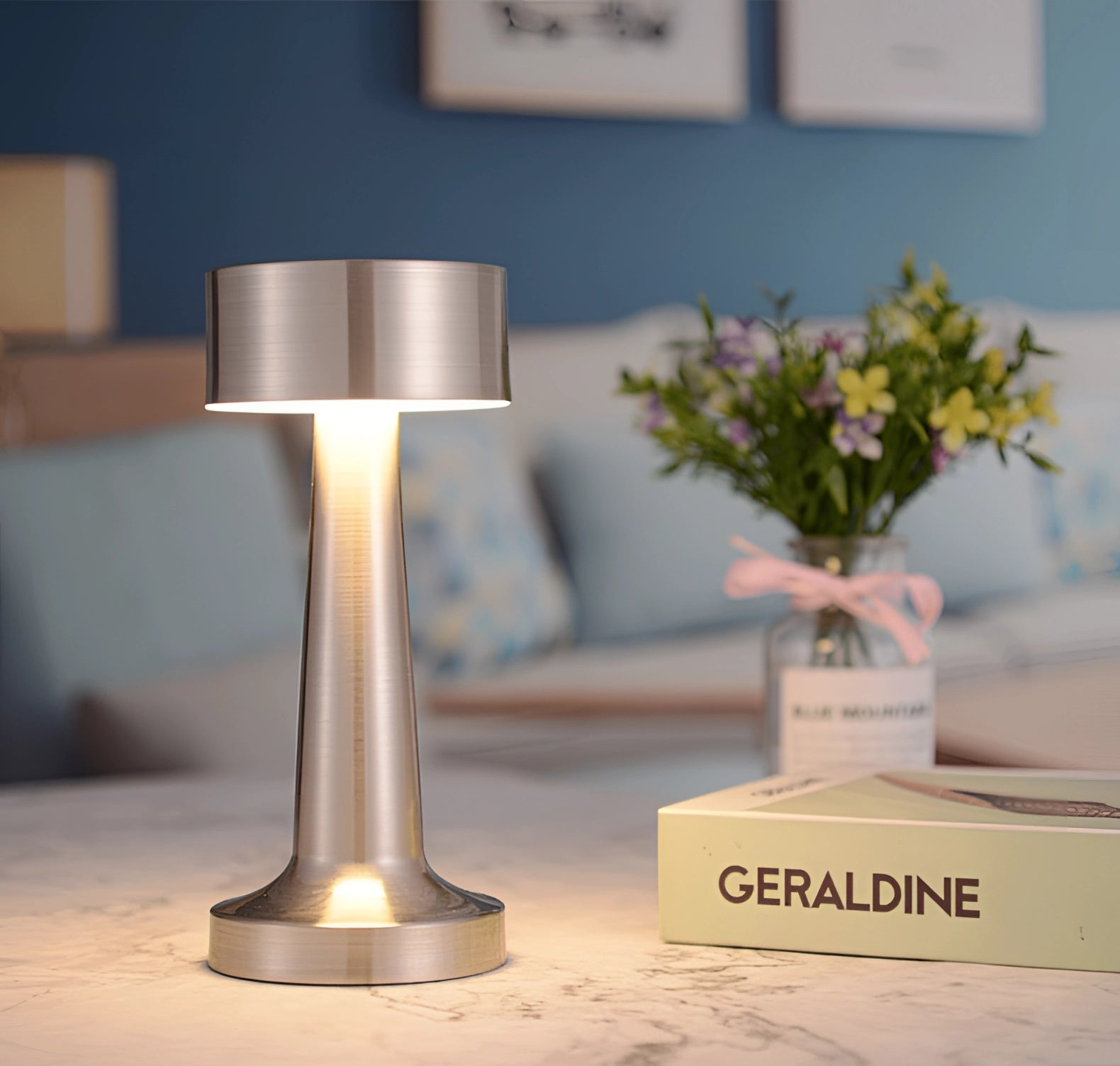 Luxury gold cordless LED table lamp with a chromed finish placed on a wooden table alongside a decorative flower vase, enhancing the elegant interior design setting.