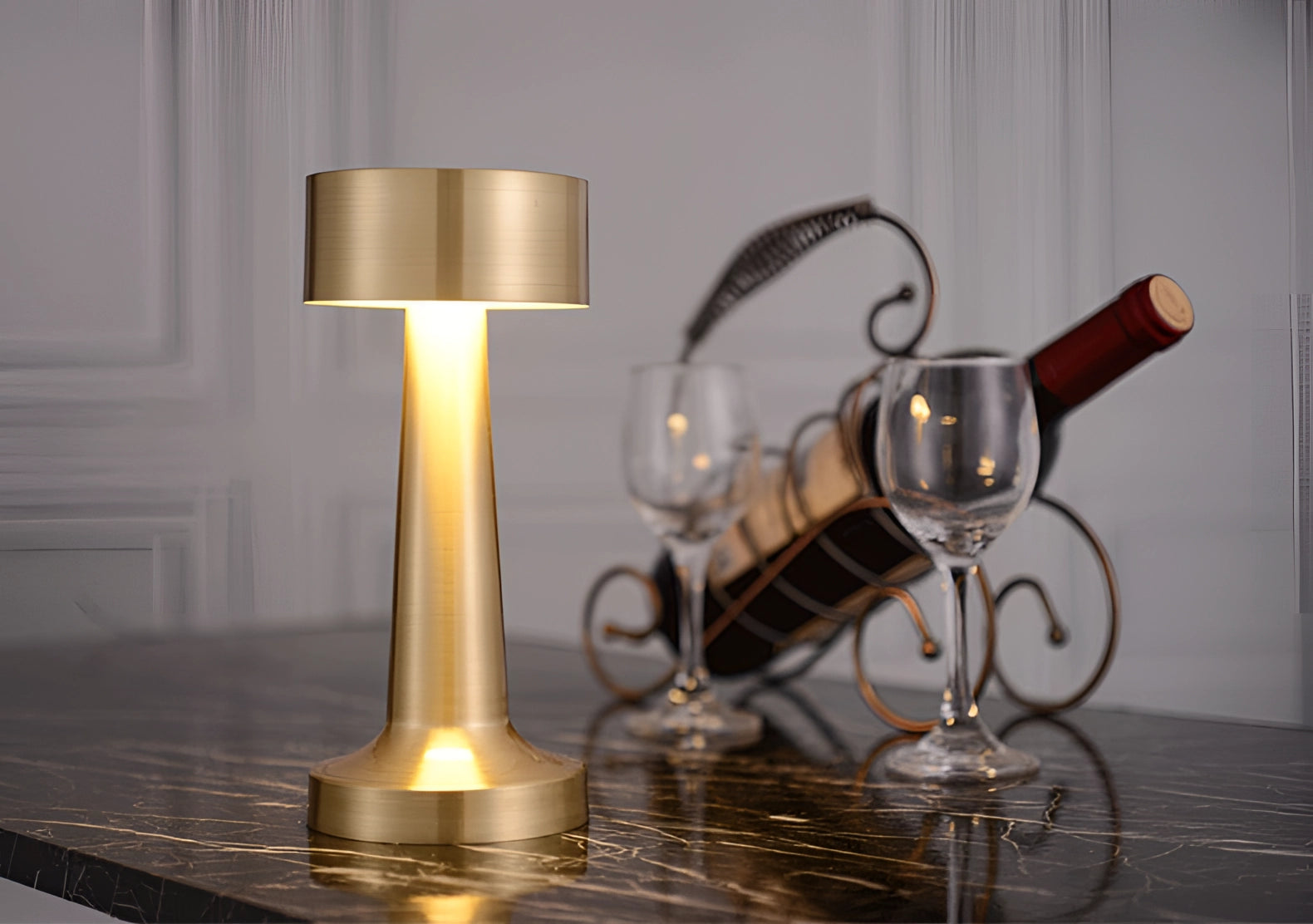 Luxury gold cordless LED table lamp with a sleek, modern design featuring a metallic finish and a glass element, designed for portability and rechargeable use, resembling a candle holder suitable for ambient lighting in events or home settings.