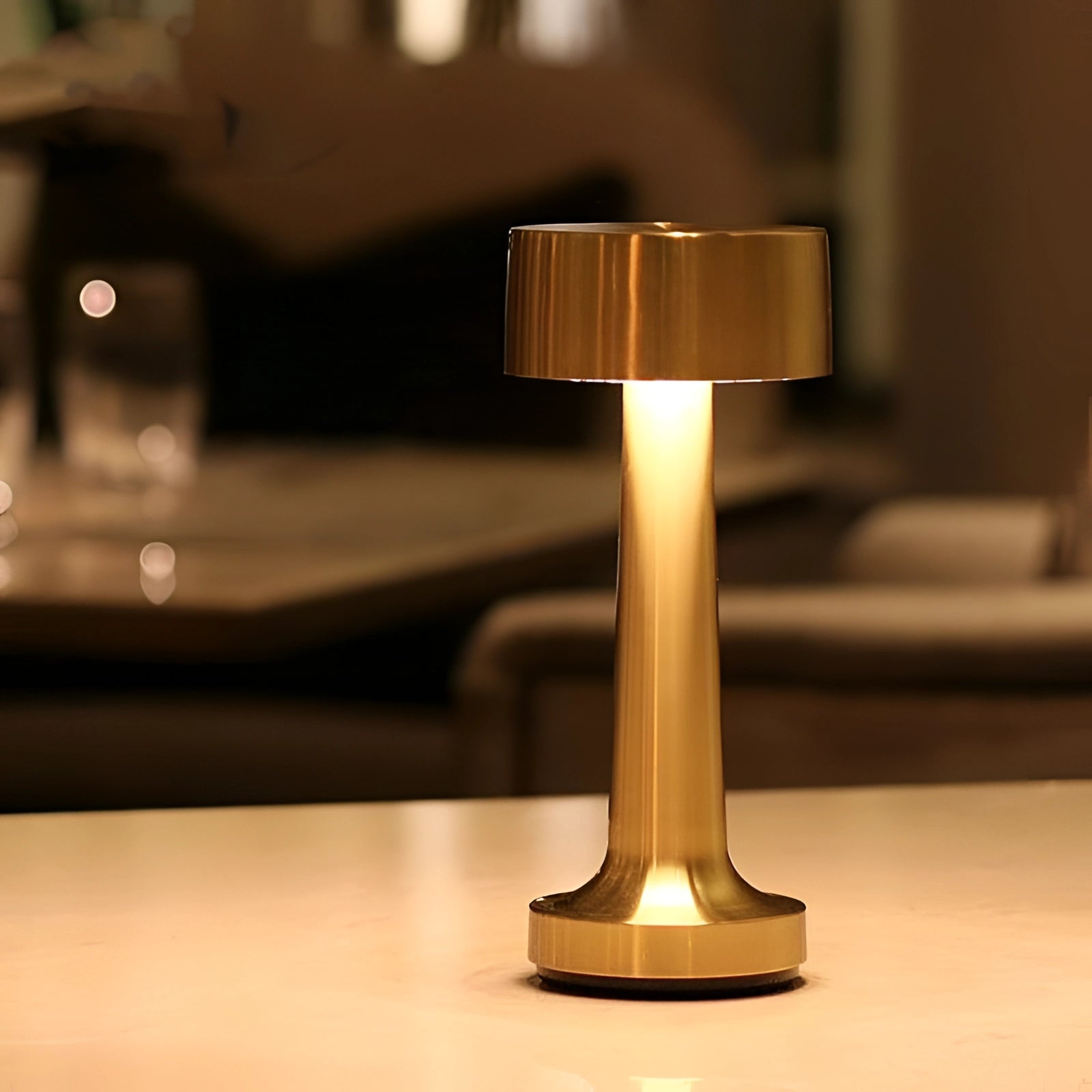 Luxury gold cordless LED table lamp with a sleek wooden base and glass lampshade, designed for portability and rechargeable use, elegantly displayed on a table in a room setting.