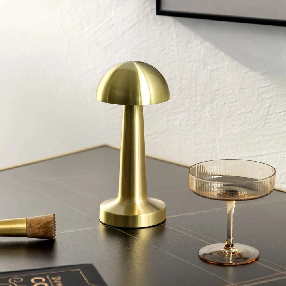 Luxury gold cordless table lamp with a sleek design, placed on a wooden surface, providing elegant lighting for dining settings.