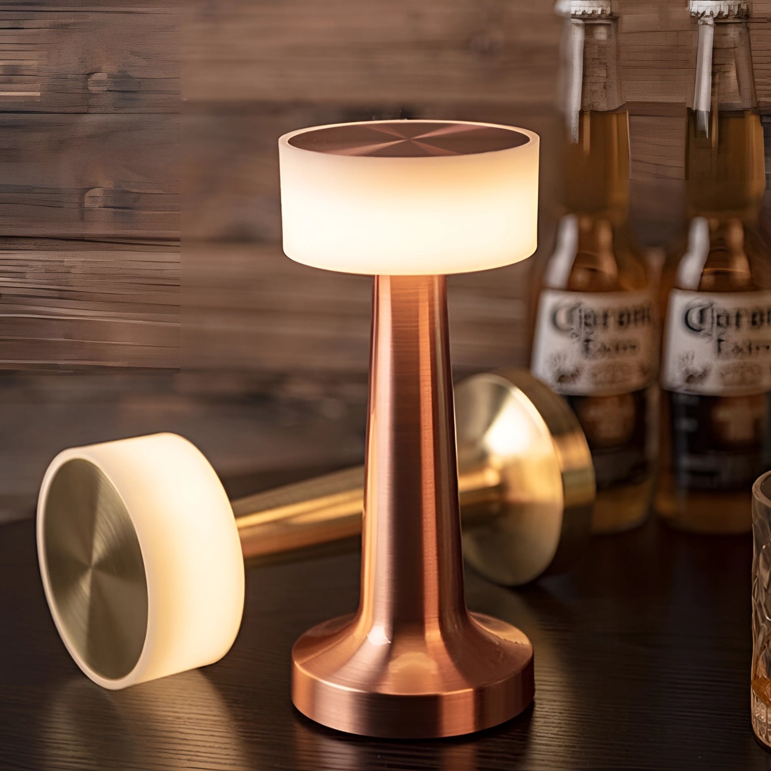 Elegant cordless table lamp in gold, illuminating a dining setting with stemware and drinkware on a wooden table.