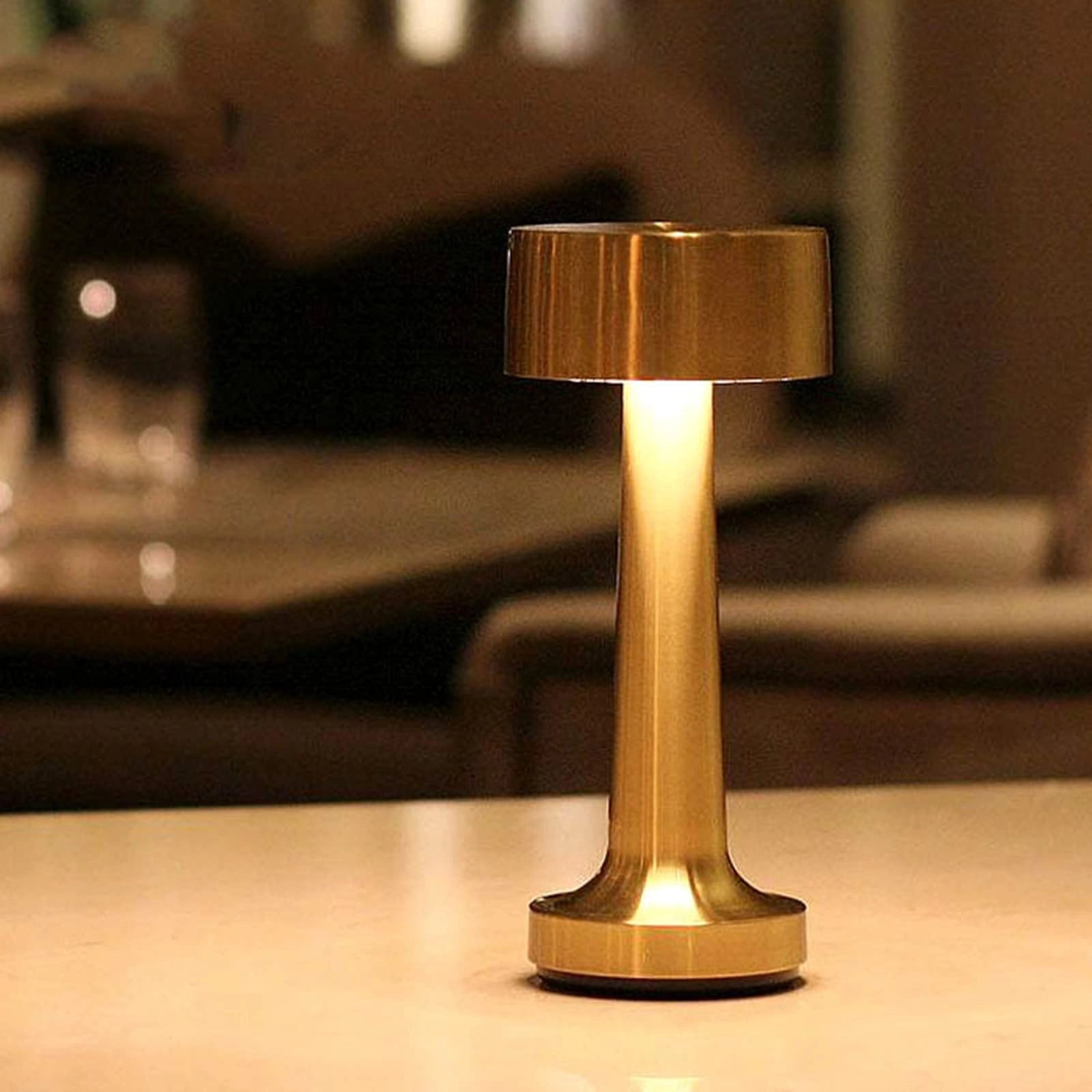 Elegant rechargeable cordless table lamp with a gold finish, featuring a wooden base, suitable for dining rooms.
