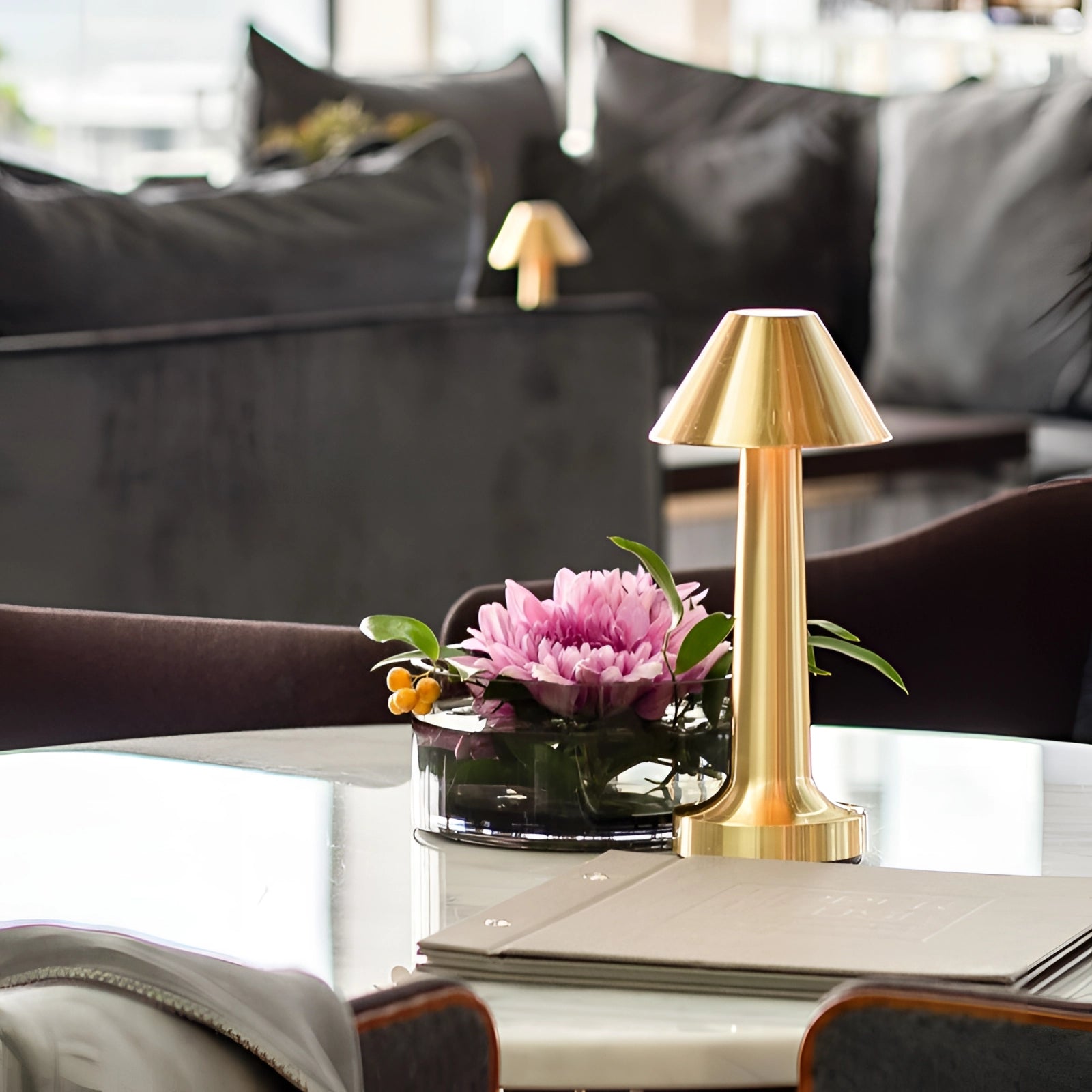 Elegant gold cordless table lamp on a dining table surrounded by purple and orange flowers, enhancing the interior design and comfort of a living room.