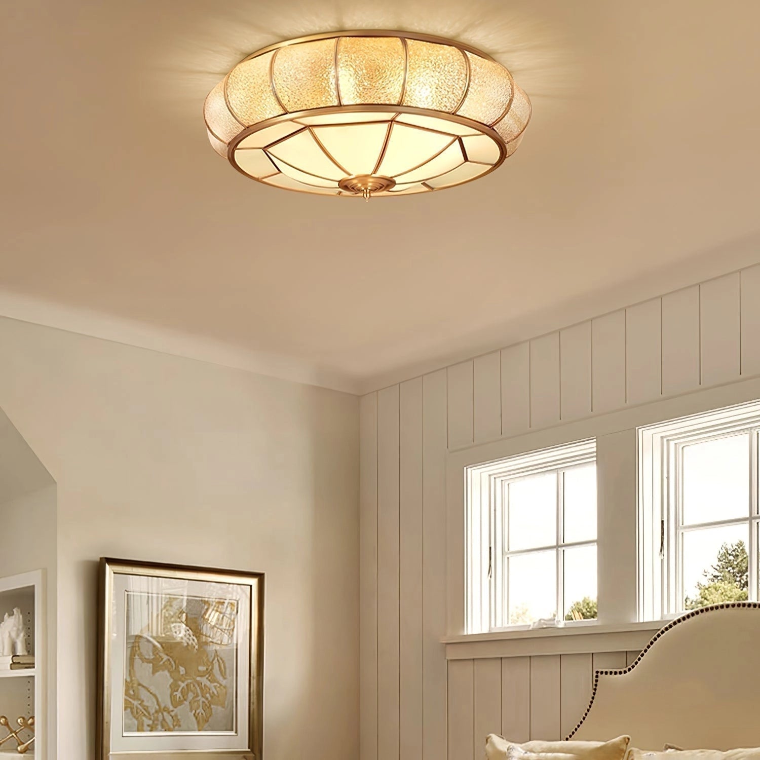 Luxurious gold flush mount ceiling light featuring textured glass and brass accents, installed on a ceiling in a stylishly designed interior space with elements such as wood and yellow walls.