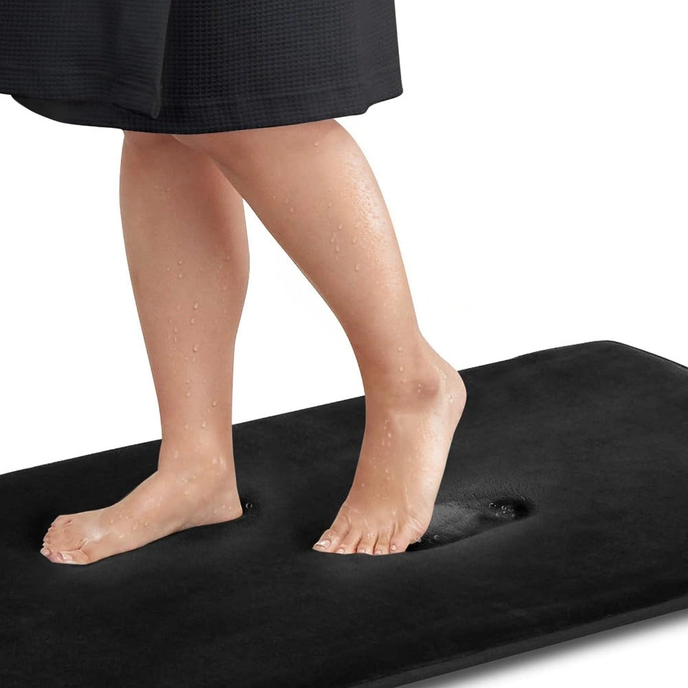 Luxury grey memory foam bath mat in extra large size (60x90cm), black color, featuring a plush and quick-dry surface with non-slip backing, shown with a barefoot person stepping on it, highlighting comfort and support for legs and feet.