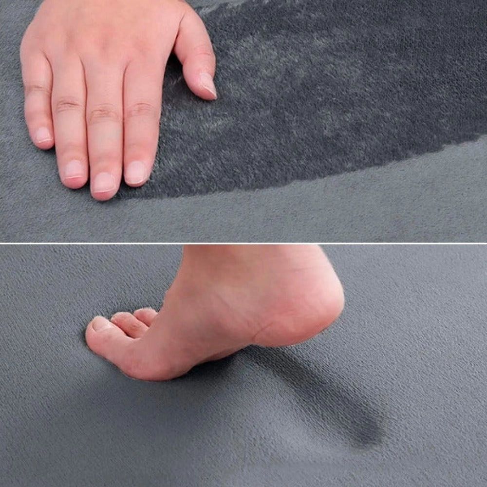Luxury grey memory foam bath mat with a plush texture, featuring a non-slip design and quick-dry capabilities, shown with a barefoot human foot stepping on it.