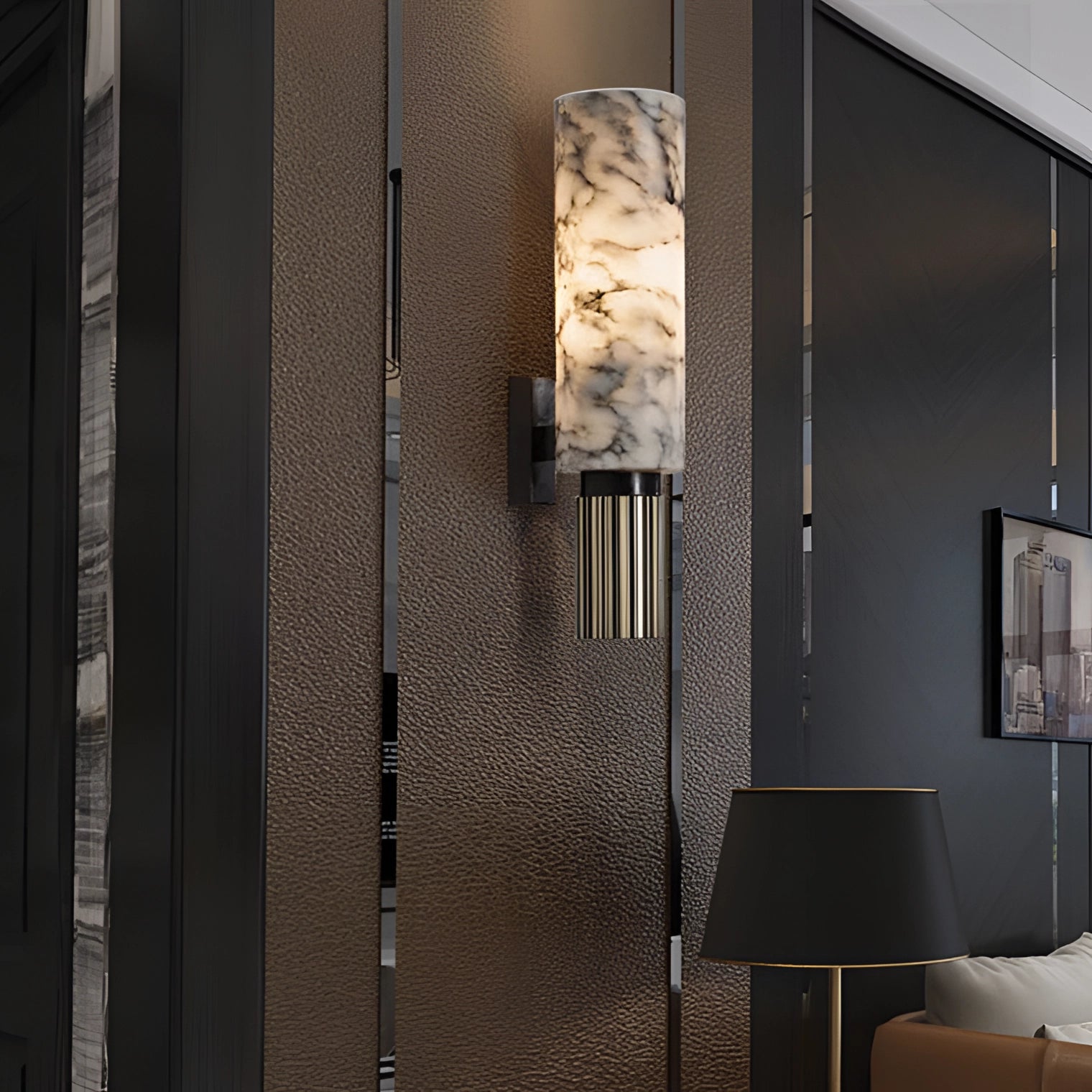 Luxury marble cylinder wall lamp mounted on a wall, illuminating a modern interior space with elegant ambient lighting, featuring a sleek design that complements contemporary decor elements such as a couch and wooden flooring.