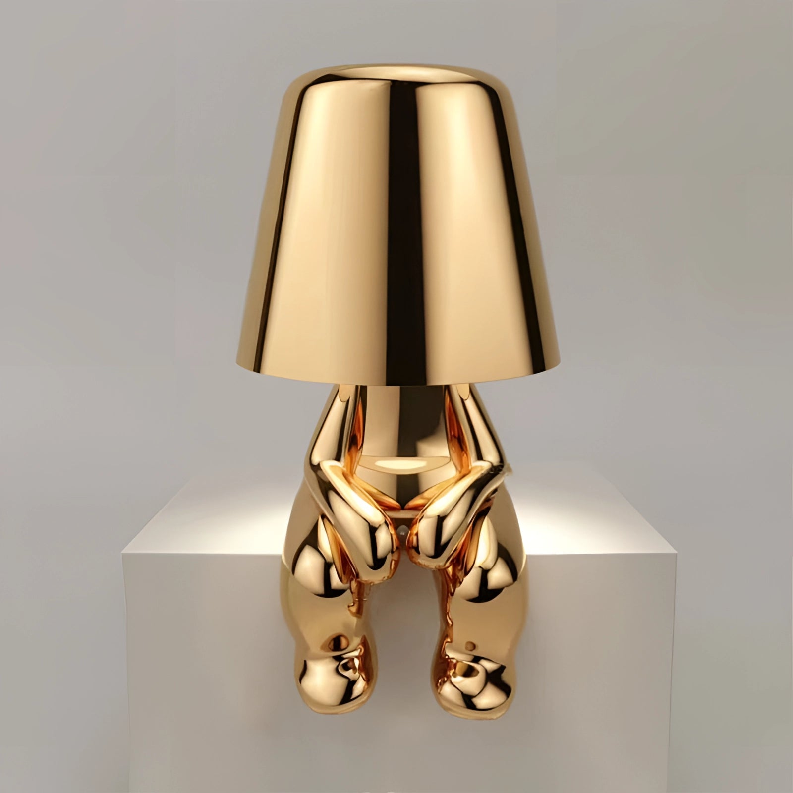 Luxury metallic gold table lamp with a modern sculptural design, featuring a rectangular lampshade and a sleek metal body, ideal for enhancing interior design aesthetics.
