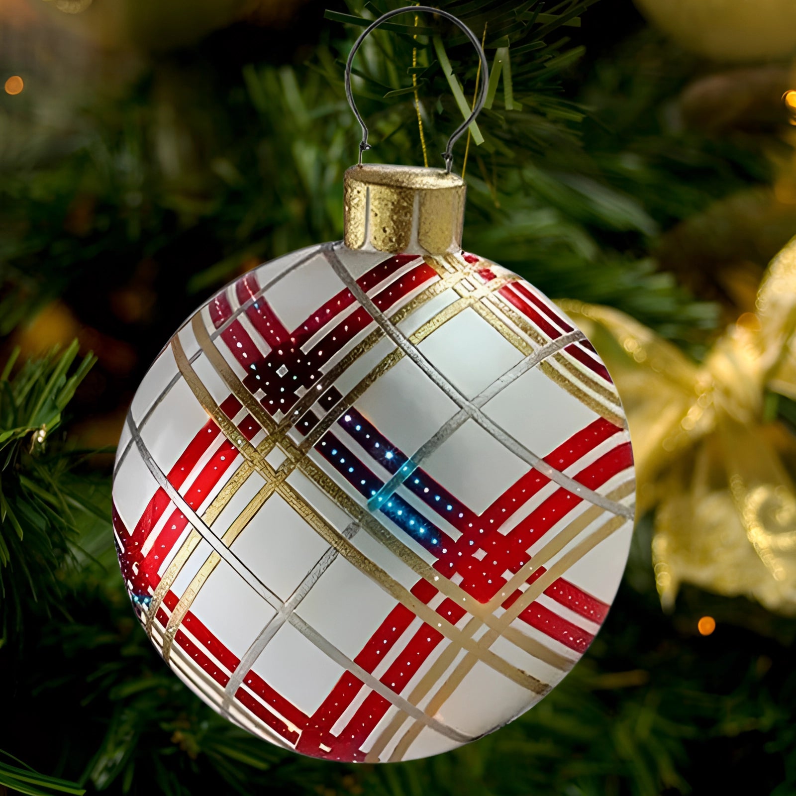 Luxury red plaid tartan glass Christmas ornament hanging on a lush evergreen tree, illuminated by festive lights, creating a warm holiday ambiance.