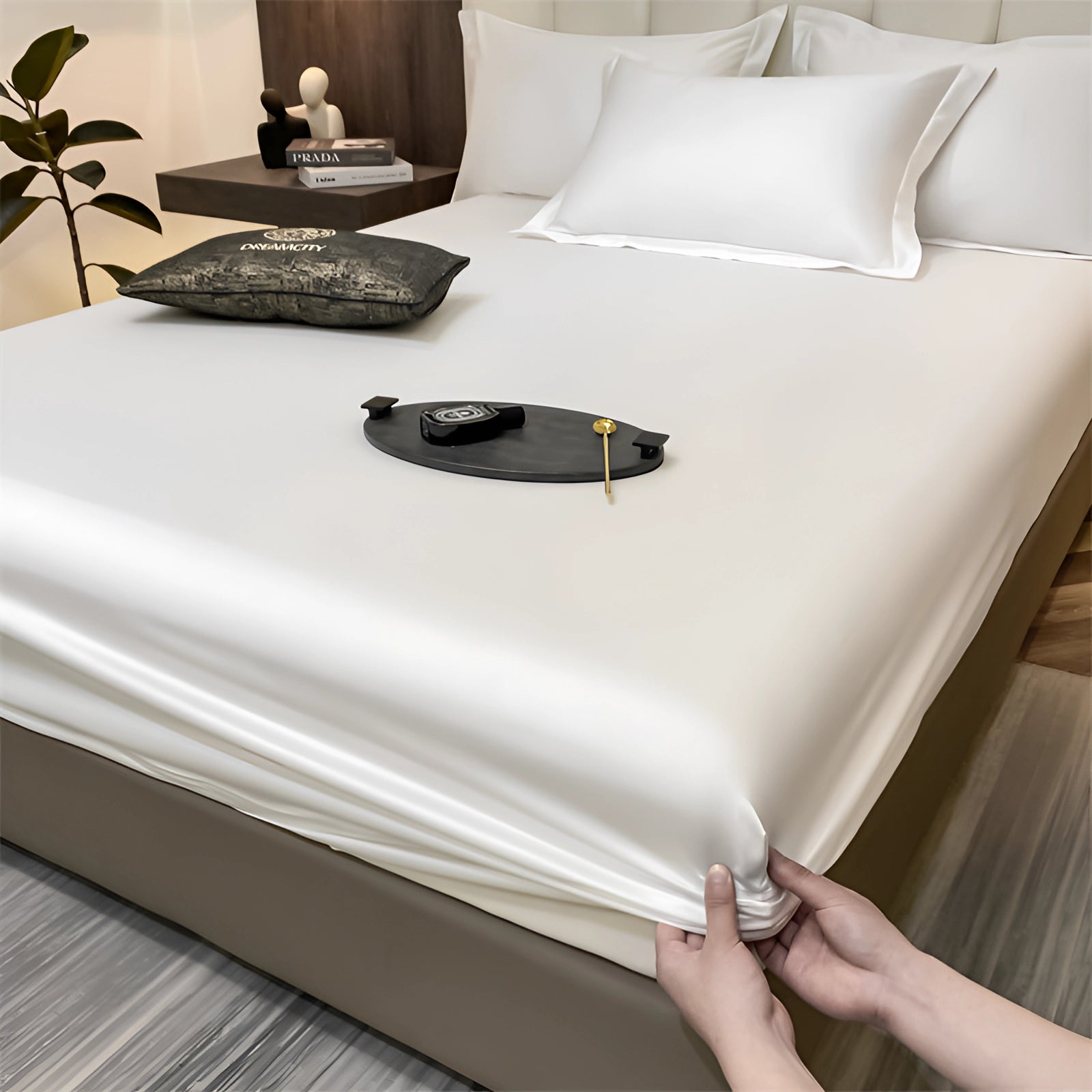Luxury red silk satin bedsheet set on display in a white color variant, featuring a wrinkle-free finish and deep pocket design, elegantly draped over a bed in a modern interior setting, with wooden furniture and a decorative plant nearby.
