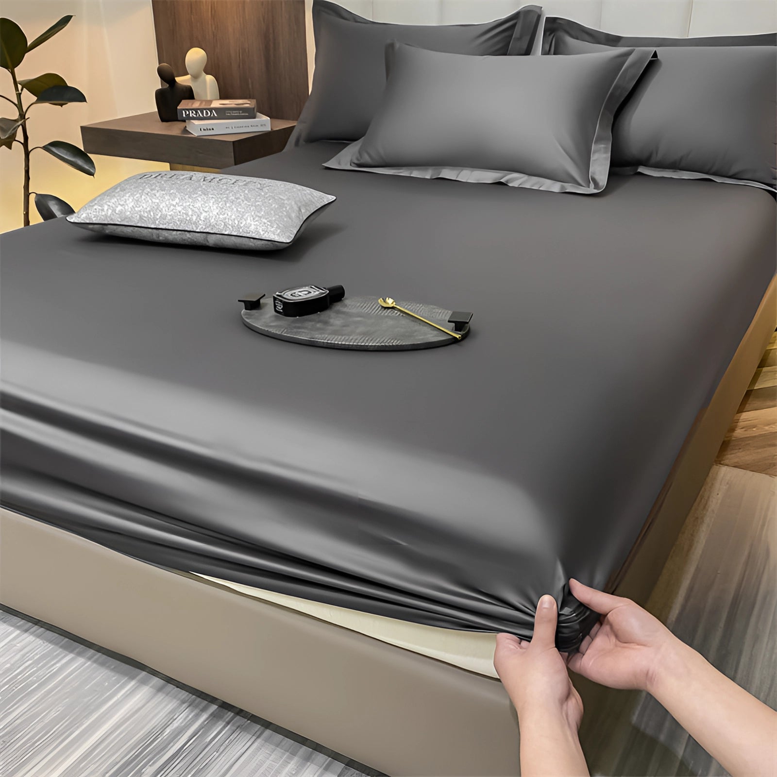Luxury red silk satin bedsheet set in dark gray, neatly spread on a bed showcasing its wrinkle-free fabric and deep pocket design, against a minimalist interior setting.