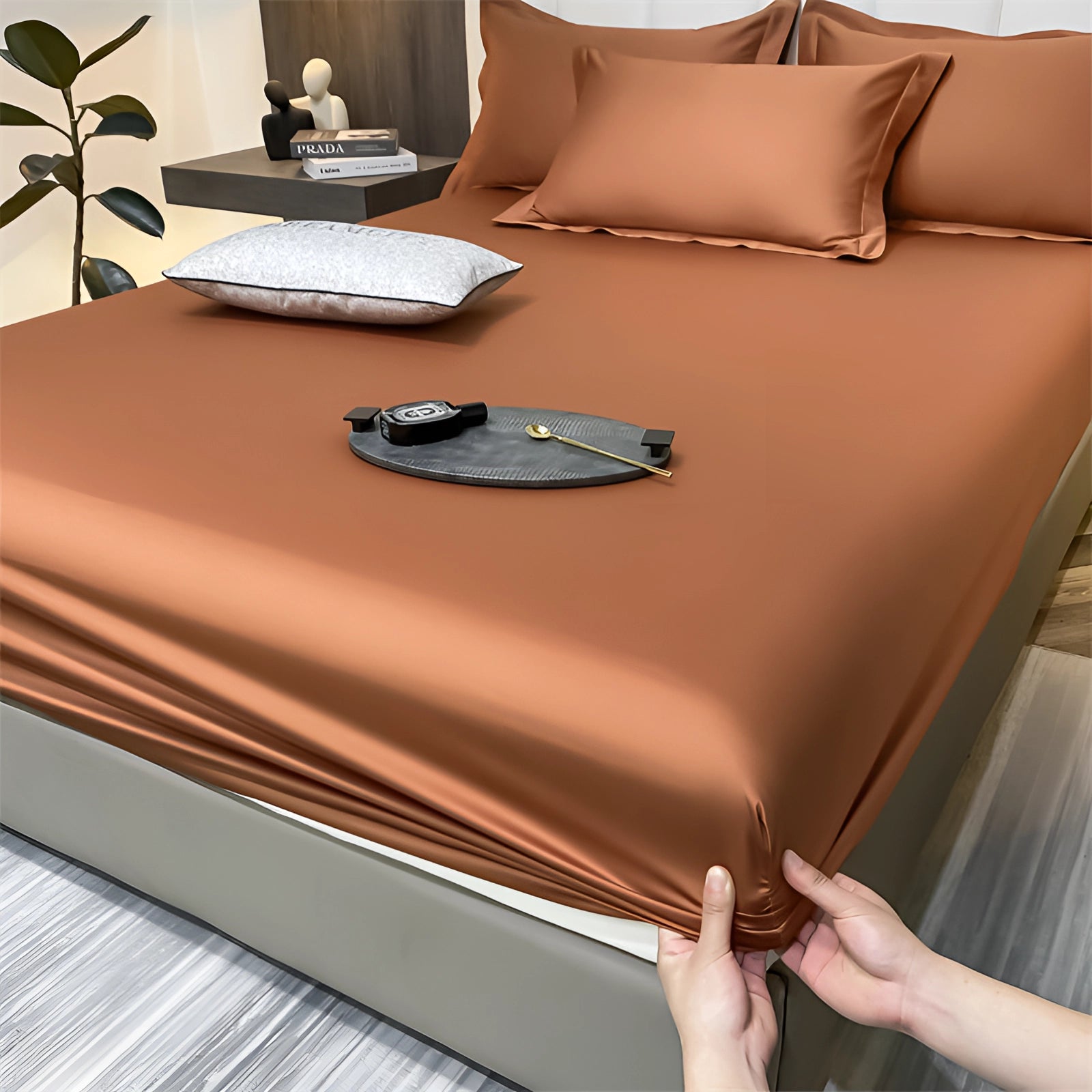 Luxury red silk satin bedsheet set displayed in an elegant bedroom setting, featuring a rich red color with a smooth, wrinkle-free finish and deep pockets, resting on a wooden bedframe with hardwood flooring.
