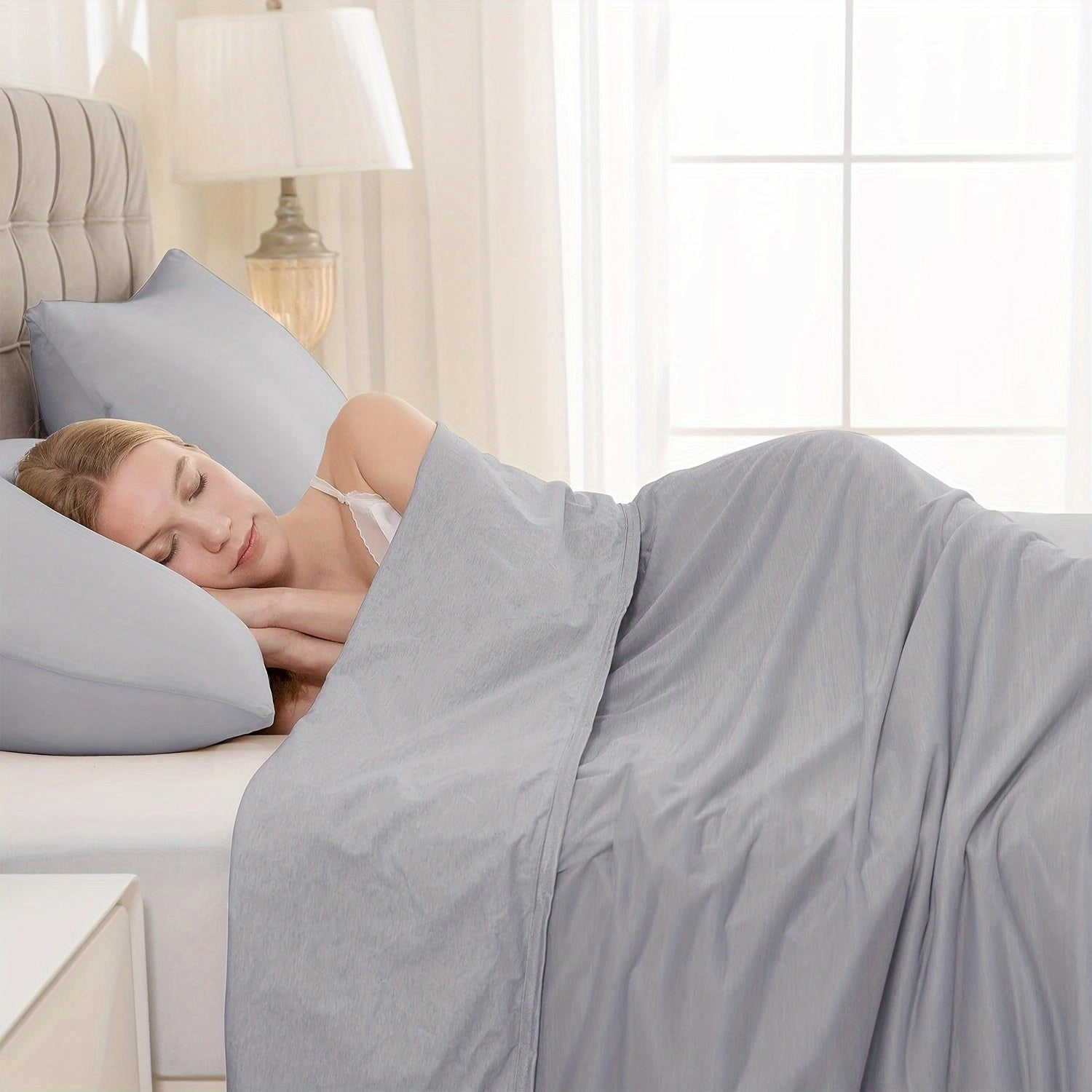 Luxurious dark gray silk comforter draped elegantly over a bed with matching pillows, showcasing a breathable, hypoallergenic, and temperature-regulating design, set in a cozy room with a wooden bed frame and soft lighting.