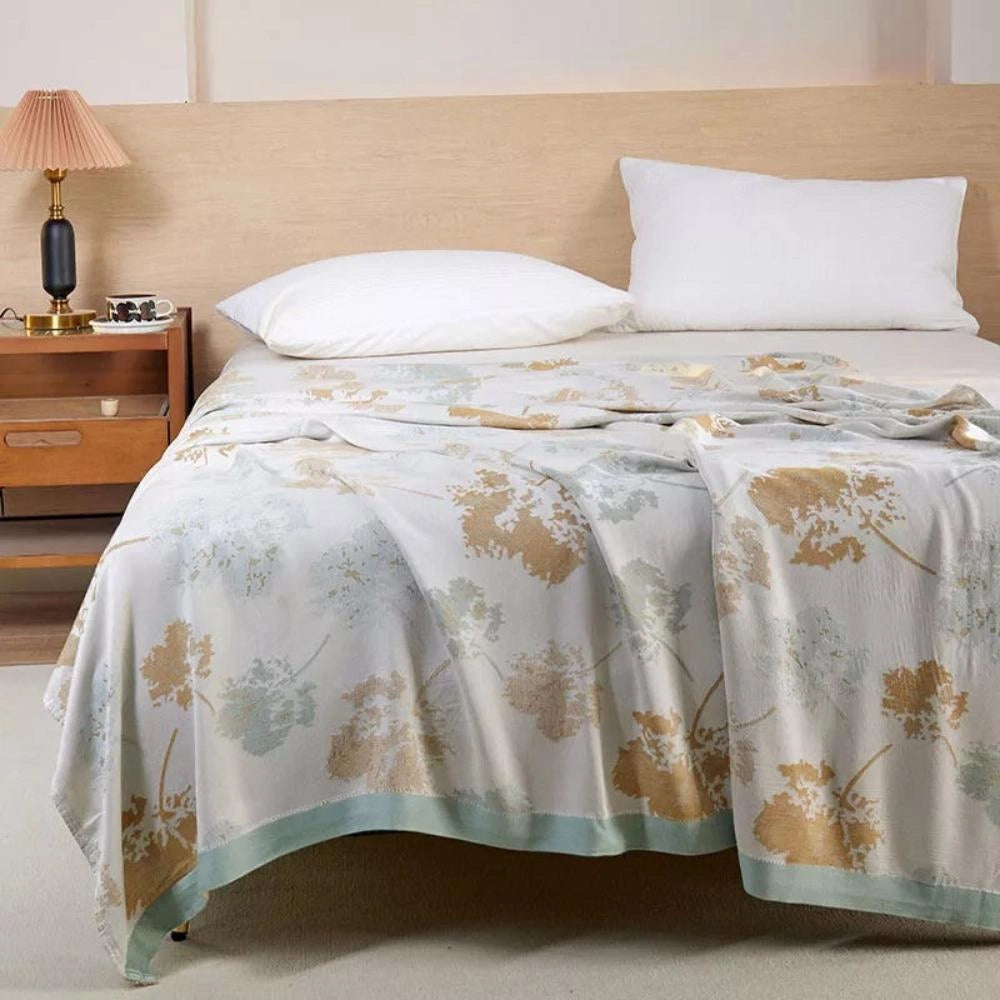 Luxury silk floral throw blanket draped over a wooden chest of drawers in an elegantly designed interior space.