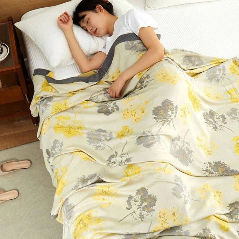 Luxurious silk throw blanket with an elegant floral pattern, ideal for enhancing home decor, draped over a bed or sofa in a stylish room setting.