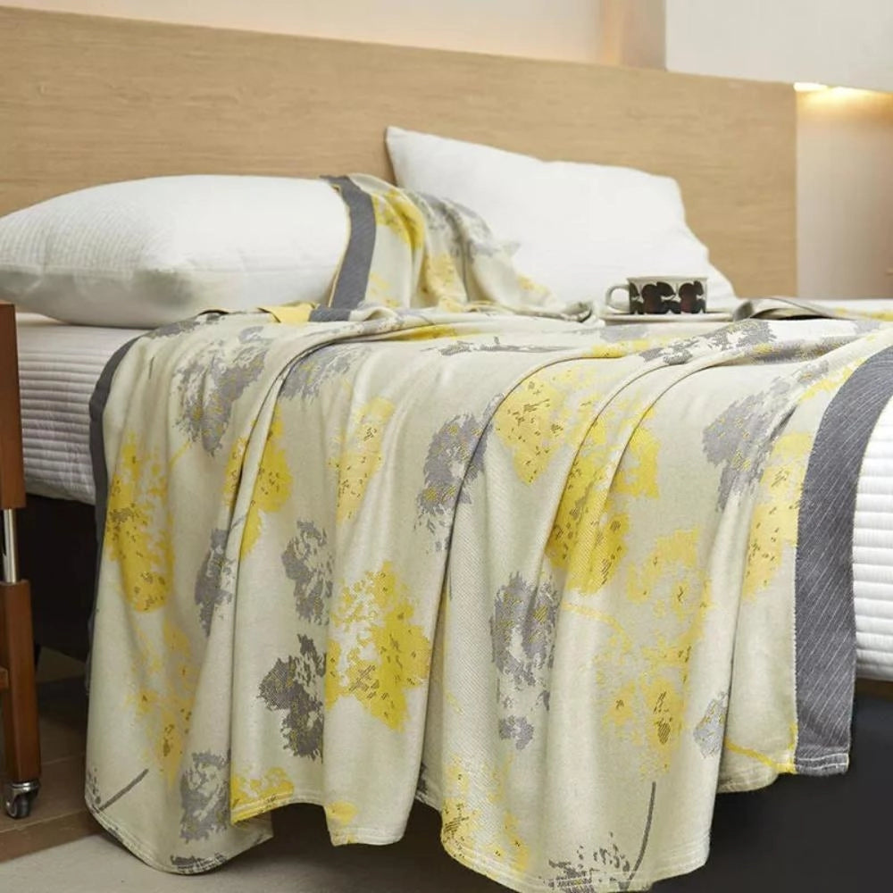 Luxury silk floral throw blanket elegantly draped over a bed, showcasing its designer appeal and adding a touch of sophistication to home decor.