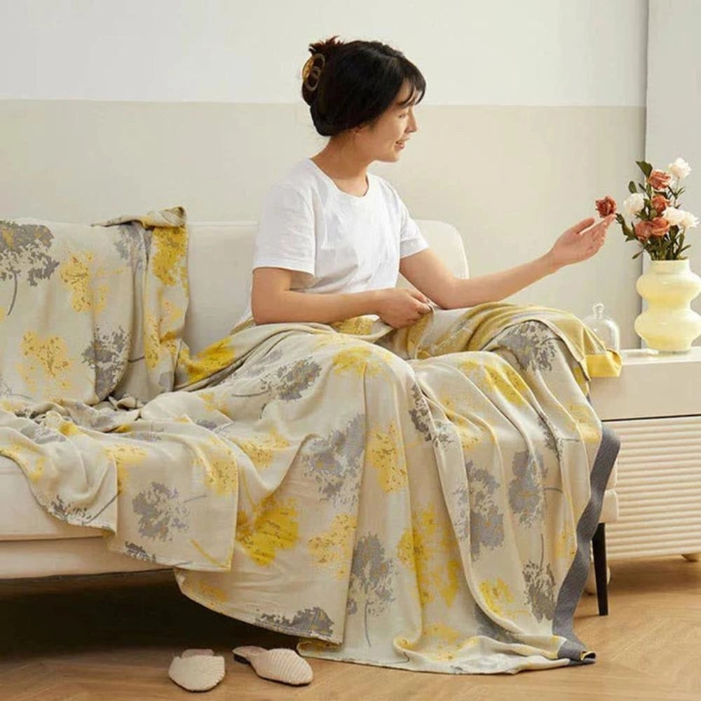 Luxurious silk floral throw blanket draped elegantly over a white sofa, showcasing intricate fashion design and providing a sense of comfort and leisure in a sophisticated home decor setting.