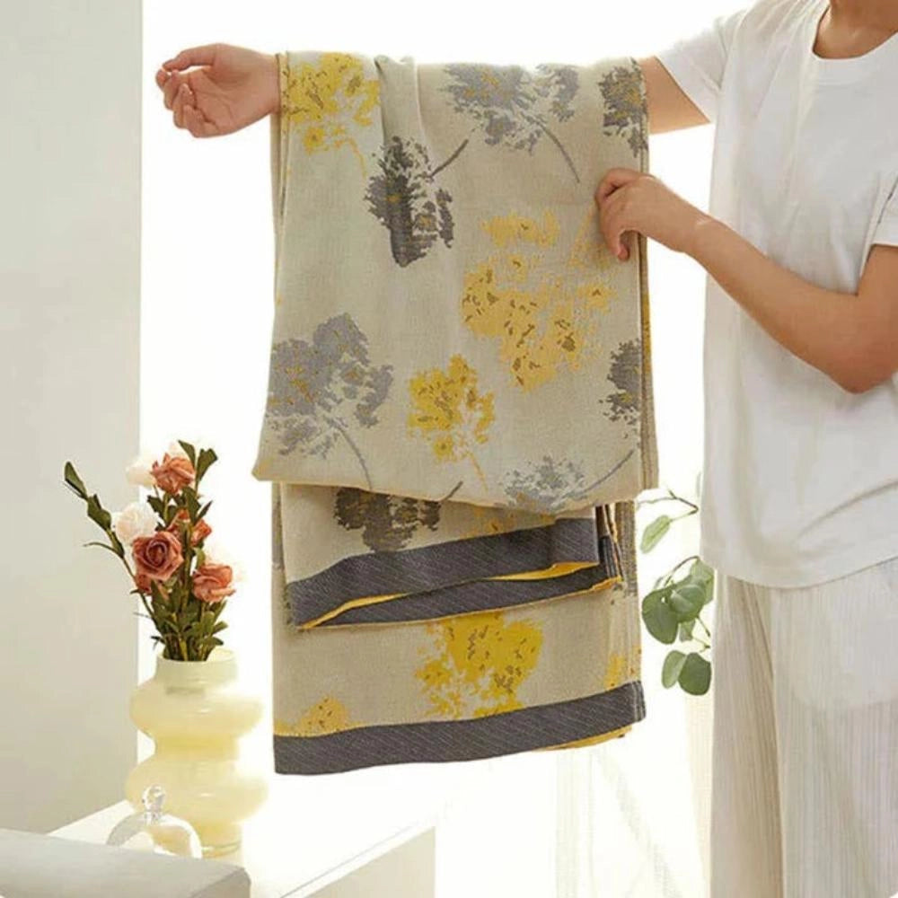 Luxurious silk floral throw blanket with an elegant design featuring intricate patterns, resembling delicate petals and plants, in a predominantly white color scheme.