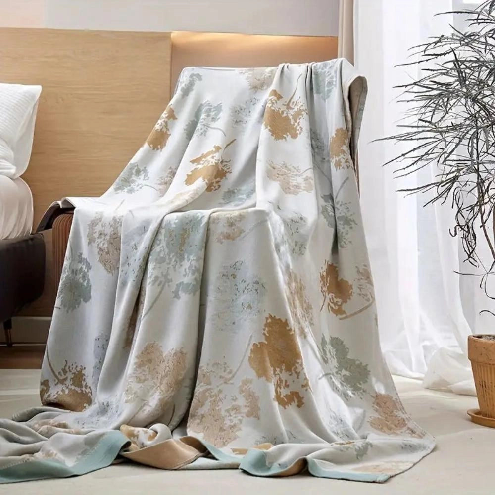Luxury silk floral throw blanket in light tan and blue, measuring 150x200cm, elegantly draped over a stylish home decor setting.