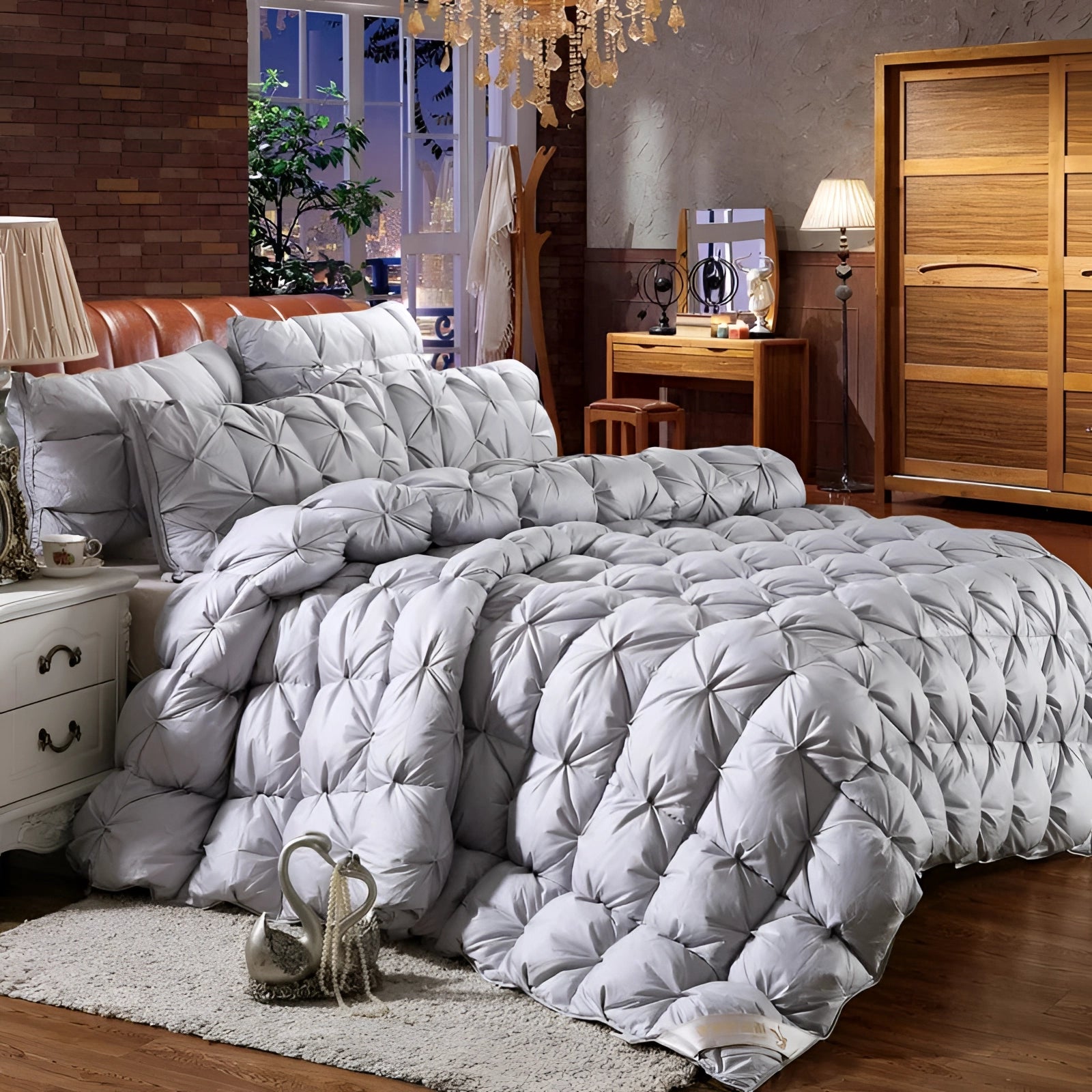 Luxury white pinch pleat comforter set in gray, elegantly displayed on a California King bed within a stylishly designed bedroom featuring wooden cabinetry, soft lighting, and lush houseplants, emphasizing comfort and sophisticated interior design.