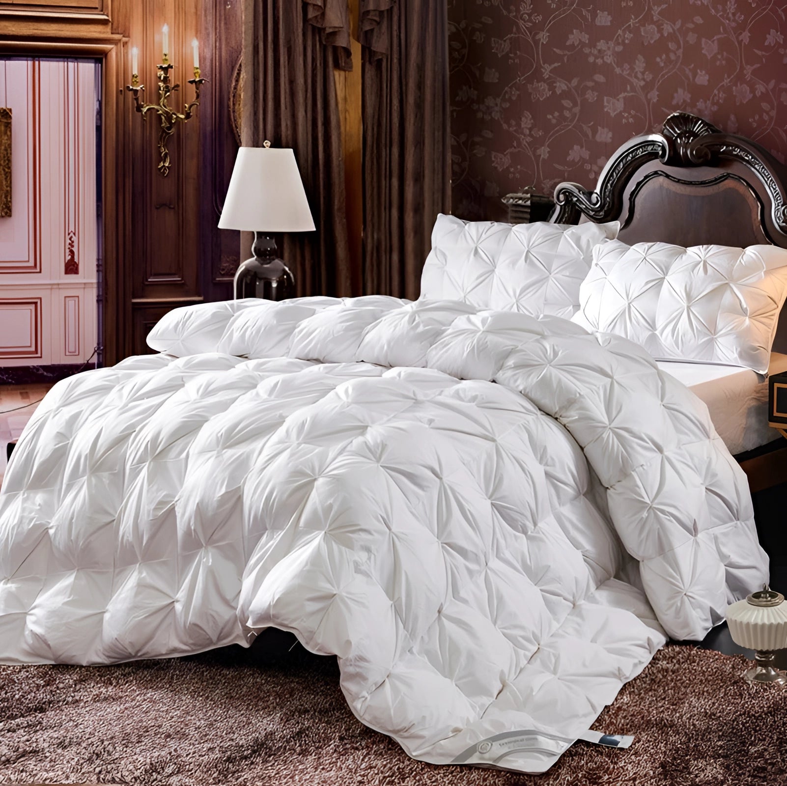Luxury white pinch pleat comforter set displayed on a bed with a stylish grey upholstered headboard, surrounded by a well-coordinated interior featuring wooden flooring, a bedside lamp, and picture frames that enhance the elegant textured bedding's appeal.