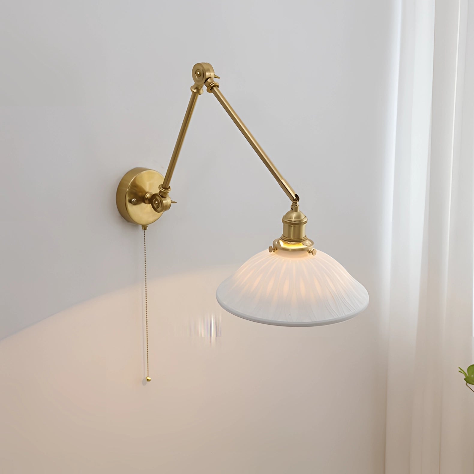 Mid-century adjustable brass wall sconce with a bowl-shaped design, featuring a beige finish and metal accents, mounted on a wall with a wooden background.