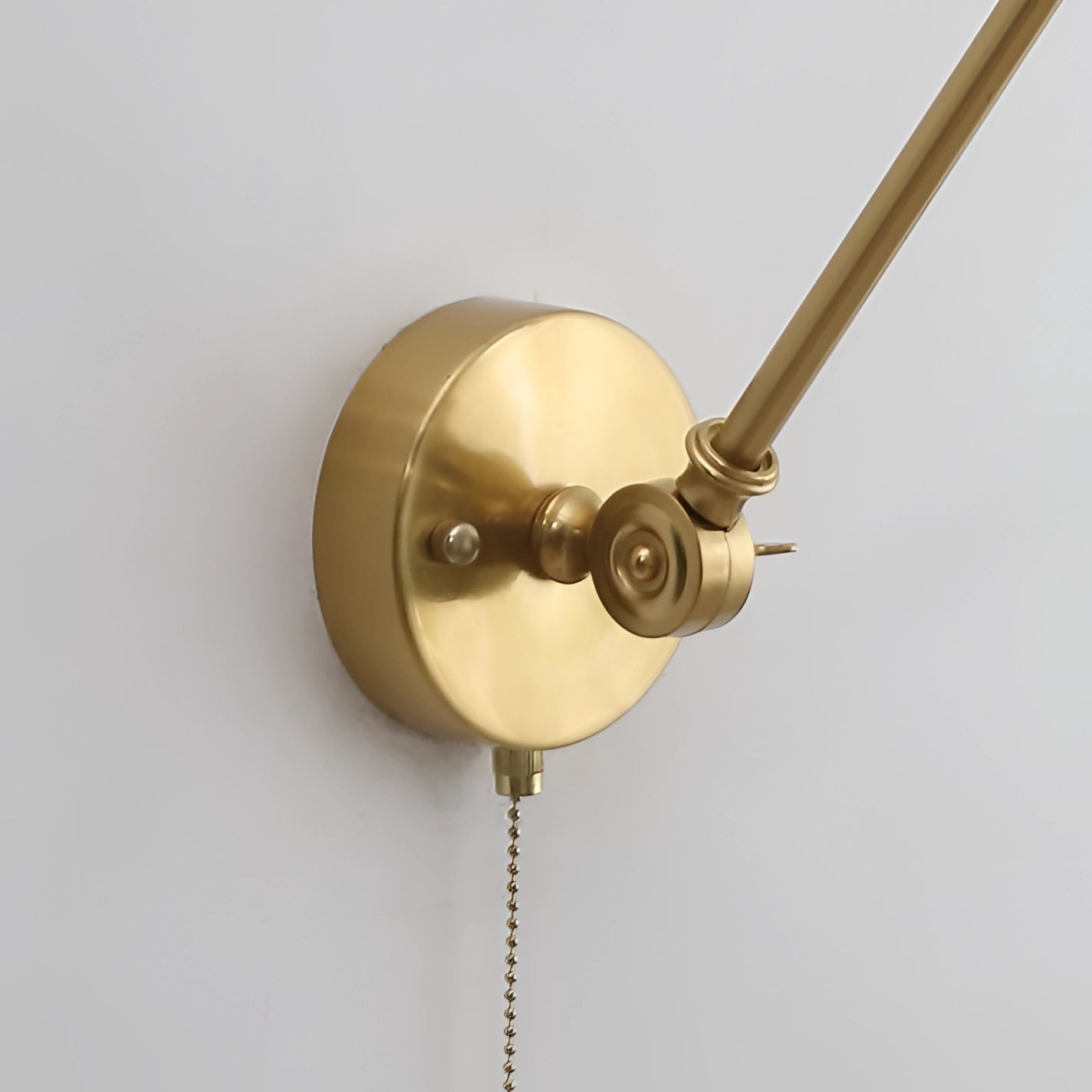 Mid-century adjustable brass wall sconce with a circular metal design, featuring a vintage aesthetic and bronze finish.