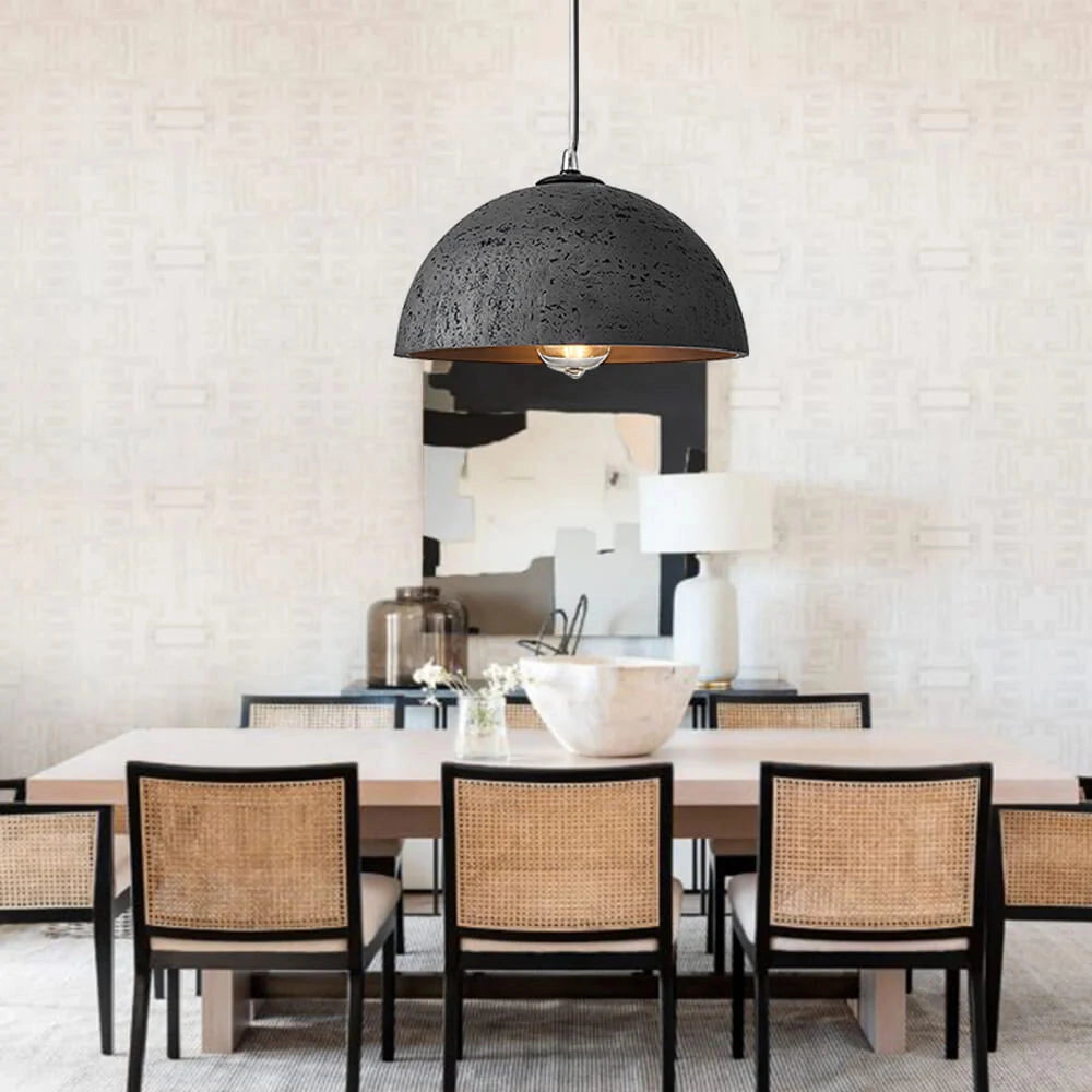 Mid-century minimalist black LED pendant light with a speckled shade, hanging above a wooden table in a modern interior setting.