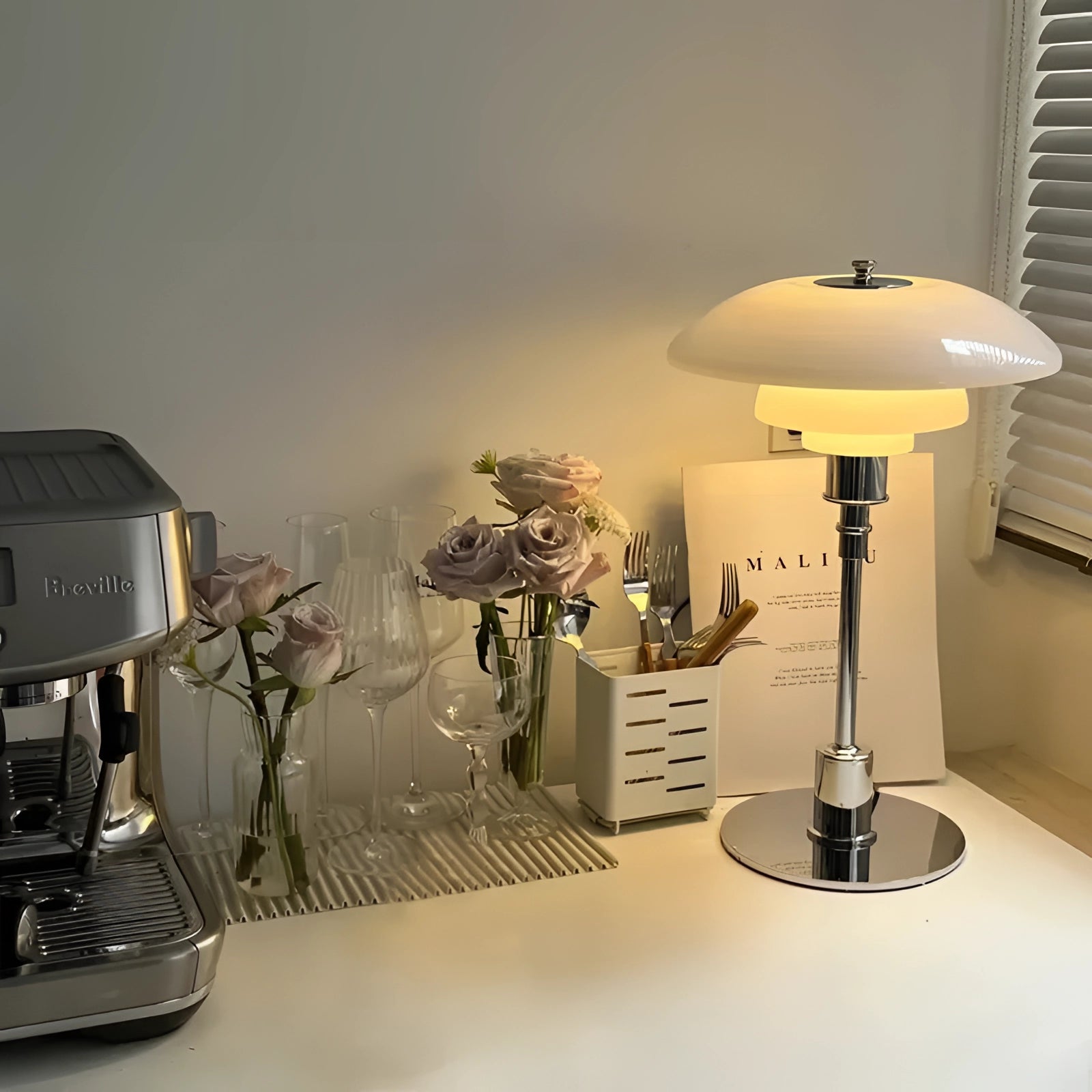 Mid-Century Modern Adjustable Brass Table Lamp with Orange Glass, featuring Danish design, placed on a wooden table next to a plant in a stylishly decorated interior space.
