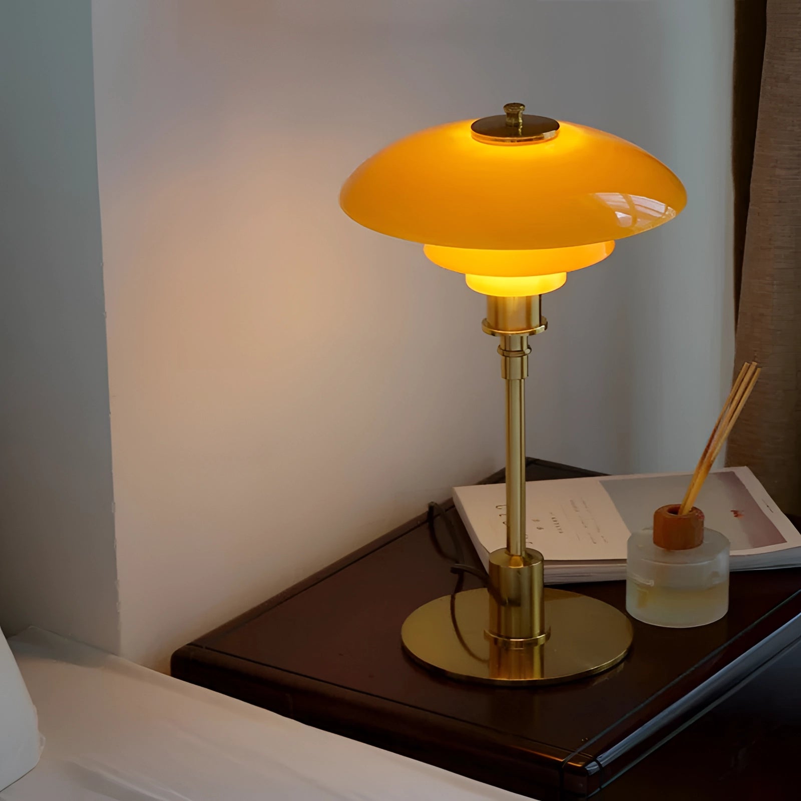 Mid-Century Modern adjustable brass table lamp with an orange glass shade, featuring Danish design elements, placed on a wooden table.