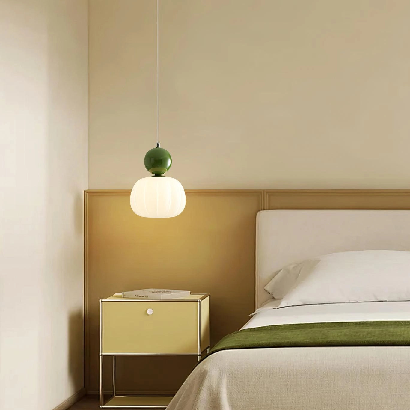 Mid-century modern amber and frosted glass pendant light fixture with green and white accents, featuring a sleek and minimalist design, suspended from a ceiling in a cozy room setting with wooden furniture and soft linens.