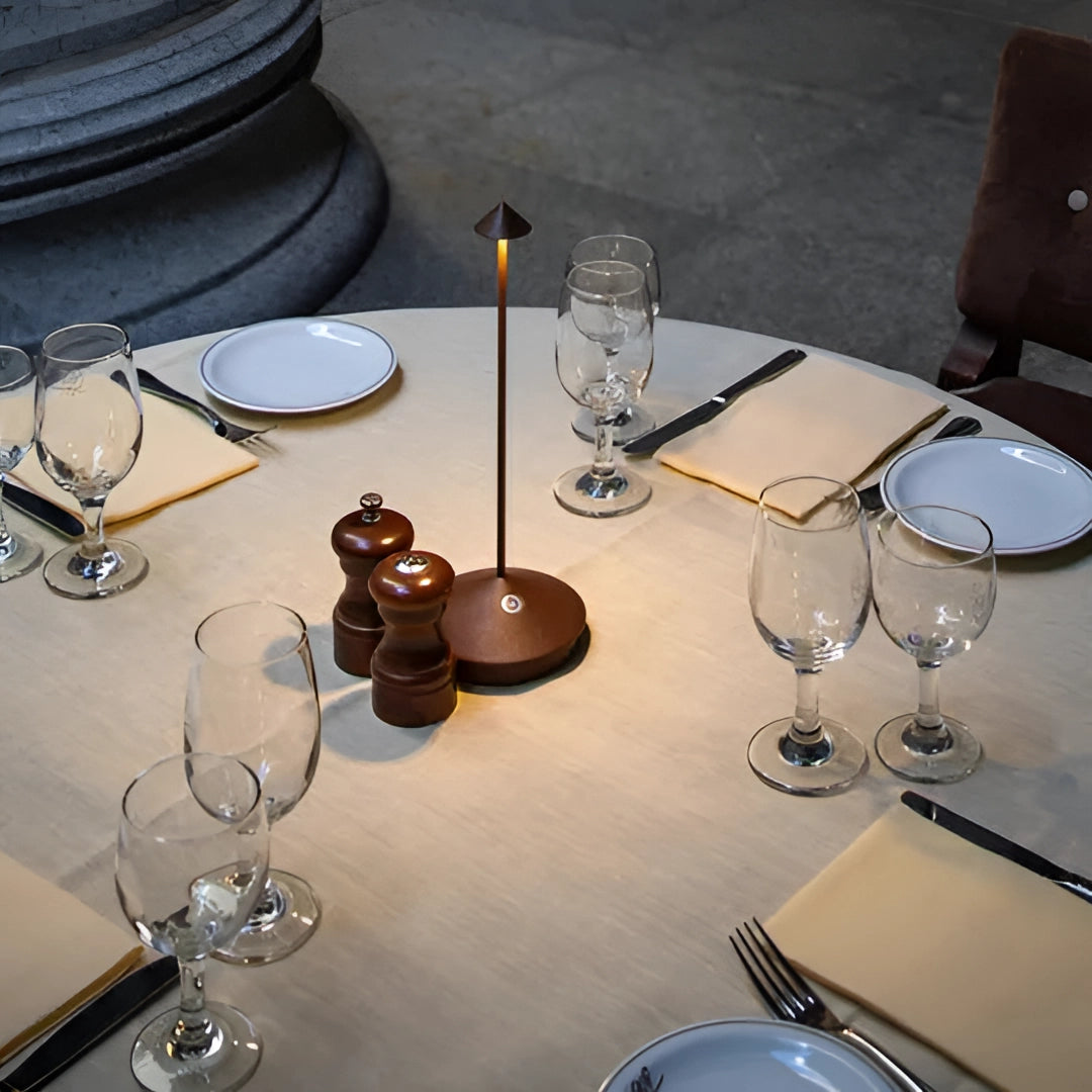 Minimalist Arrow-Shaped LED Desk Lamp placed on a modern table setting with glasses and dishware.