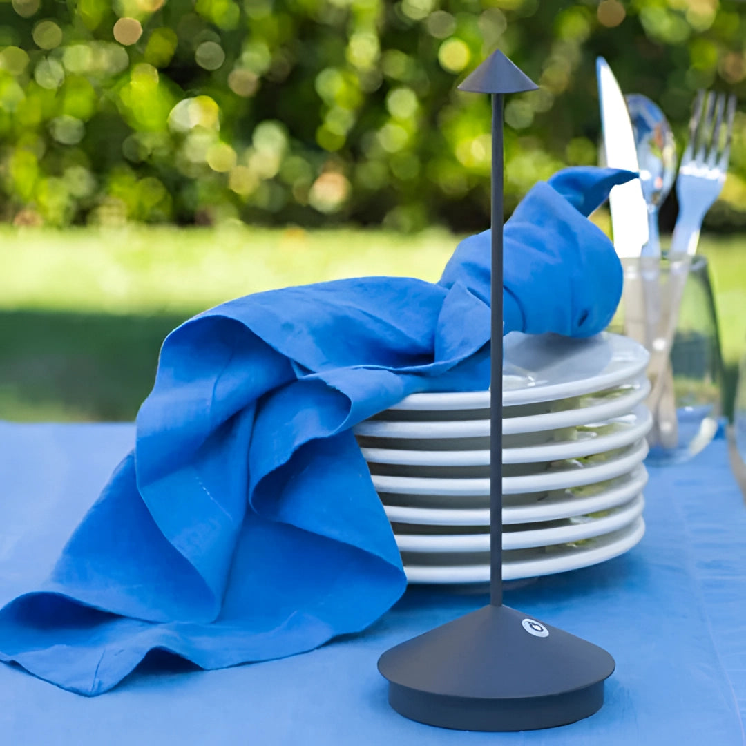 Minimalist arrow-shaped LED desk lamp in an electric blue color, designed for modern decor, placed on a table.